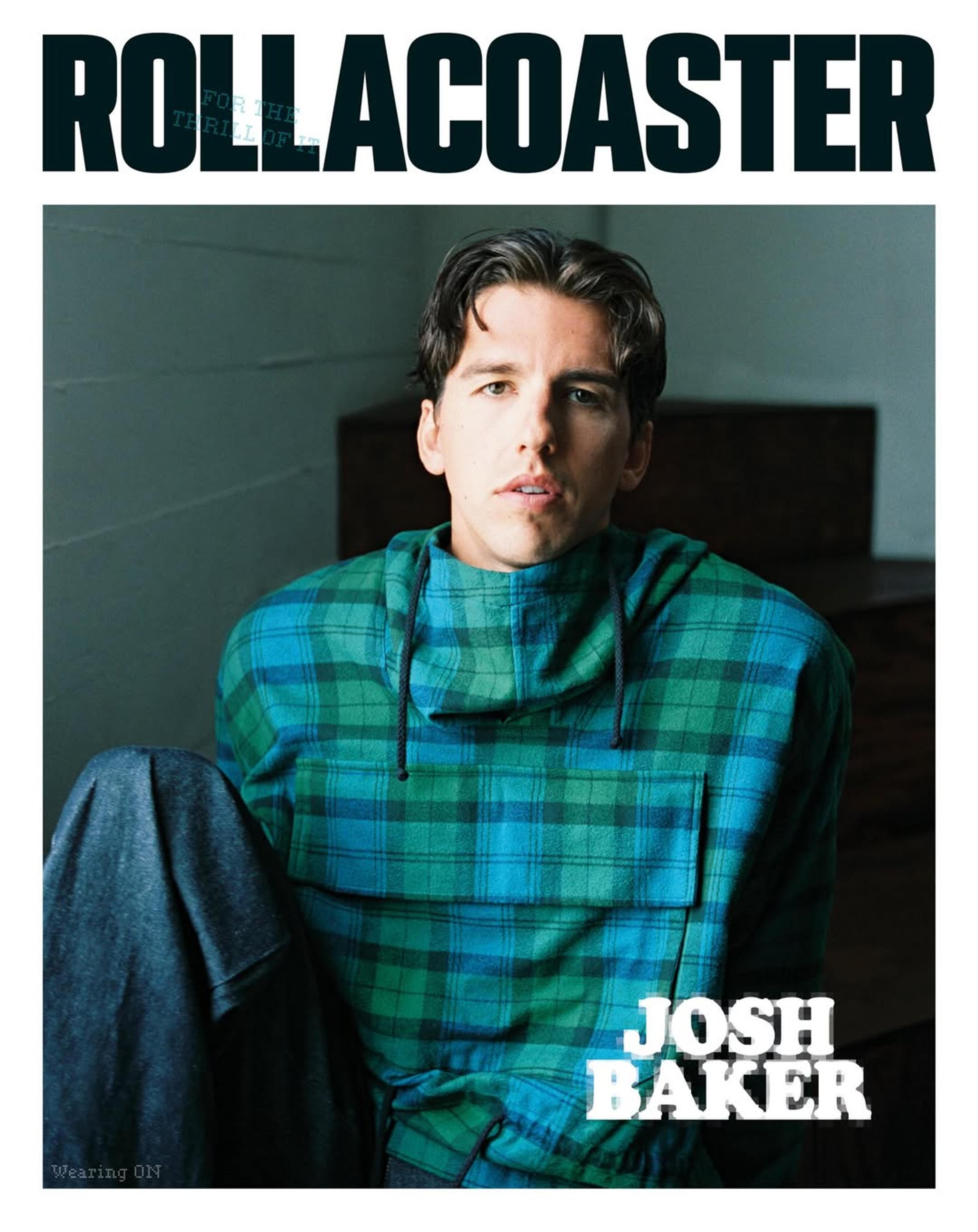 Josh Baker wearing green and blue plaid hoodie sitting down facing the camera.