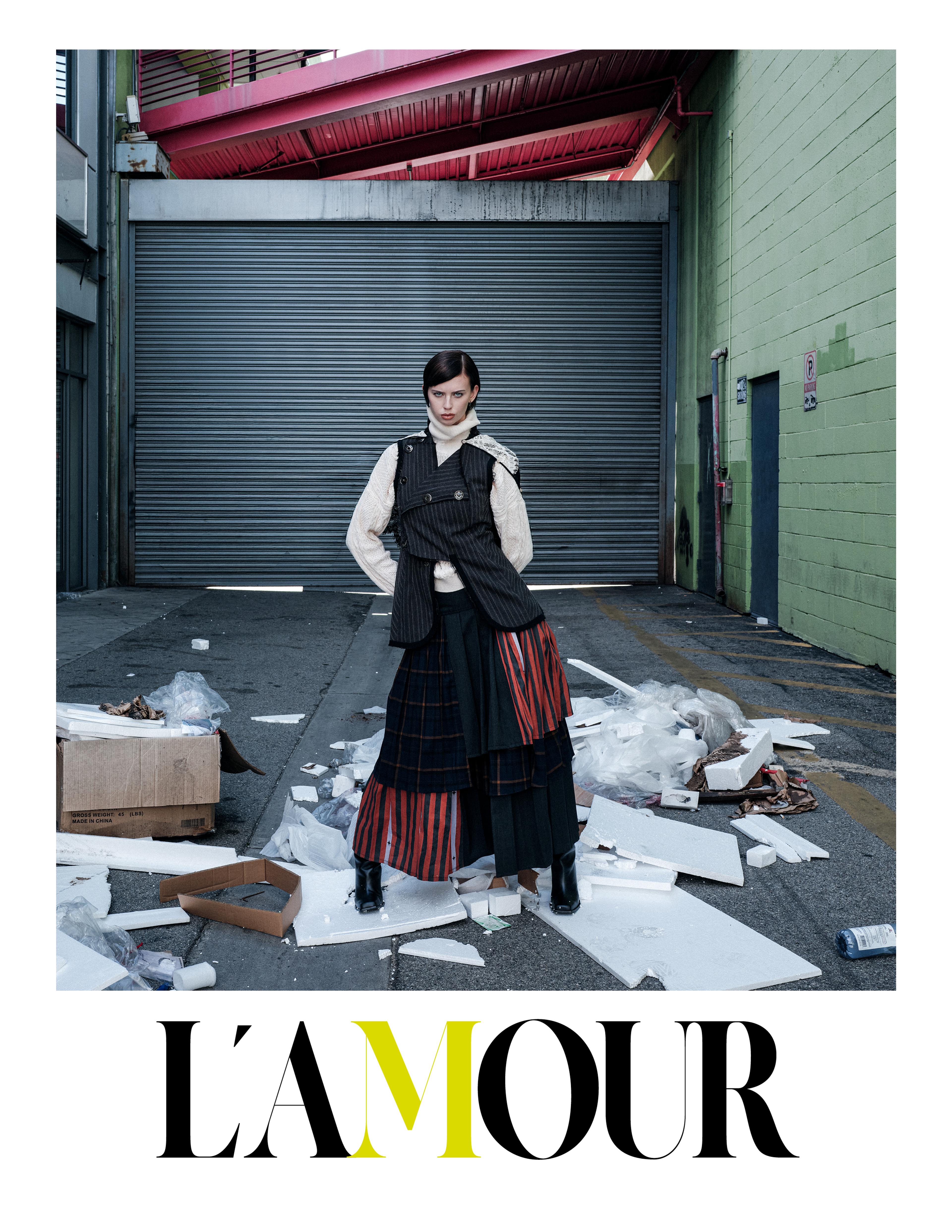 Girl with short hair wearing a layered skirt and layered lace tops in a pile of trash in an alley.