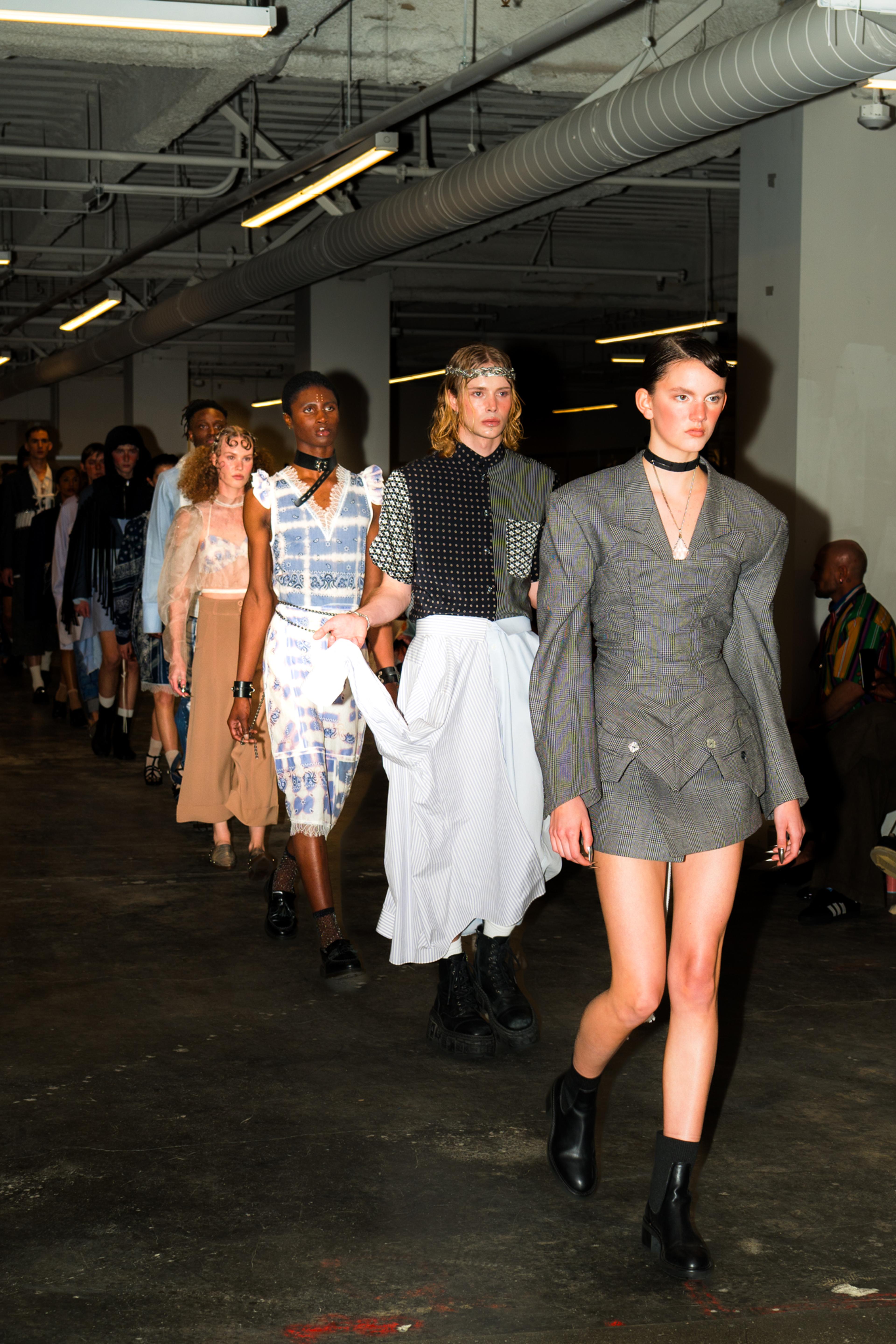 Models walking a runway wearing suiting.