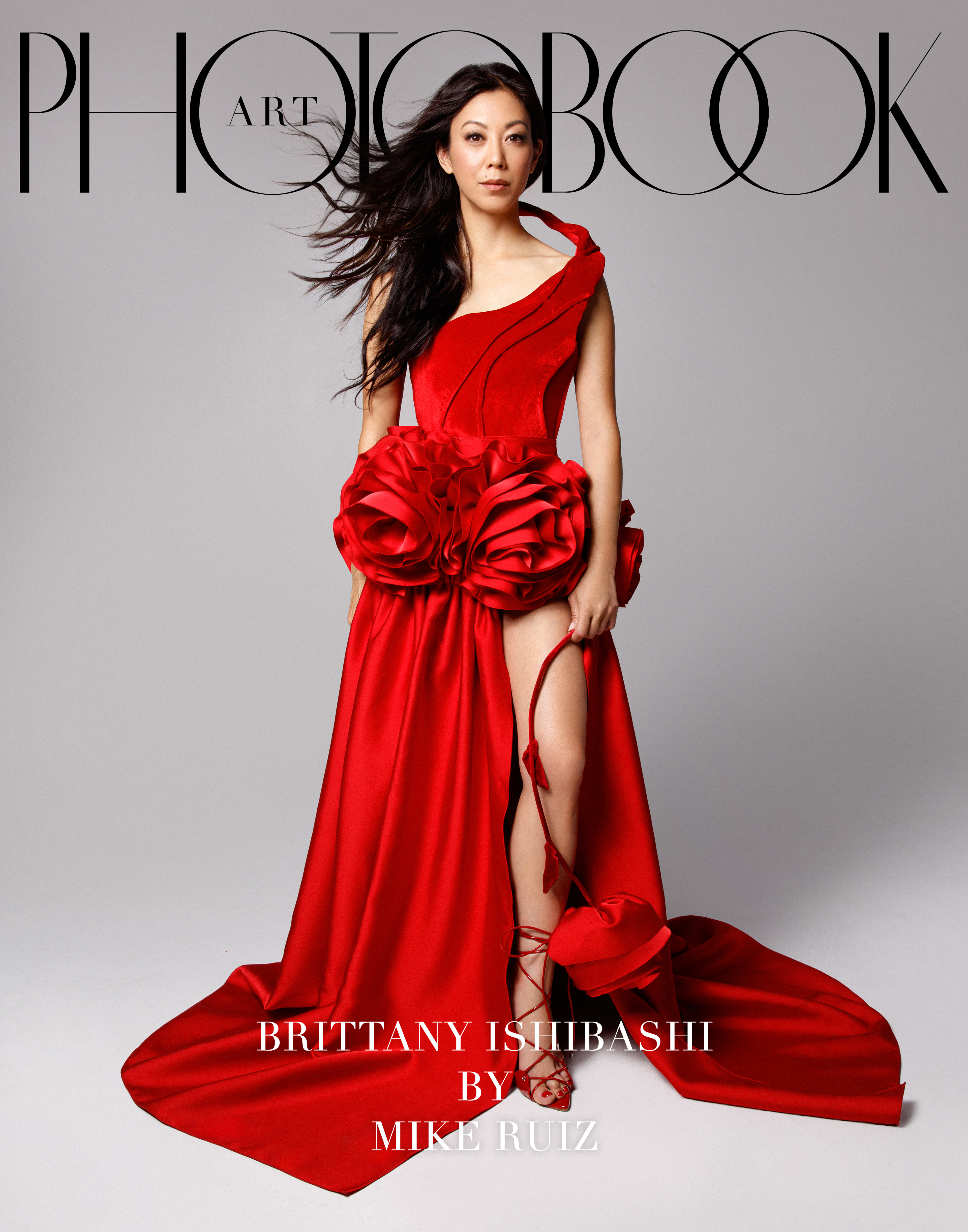 Brittany Ishibashi wearing a red dress and red shoes with hair blowing.
