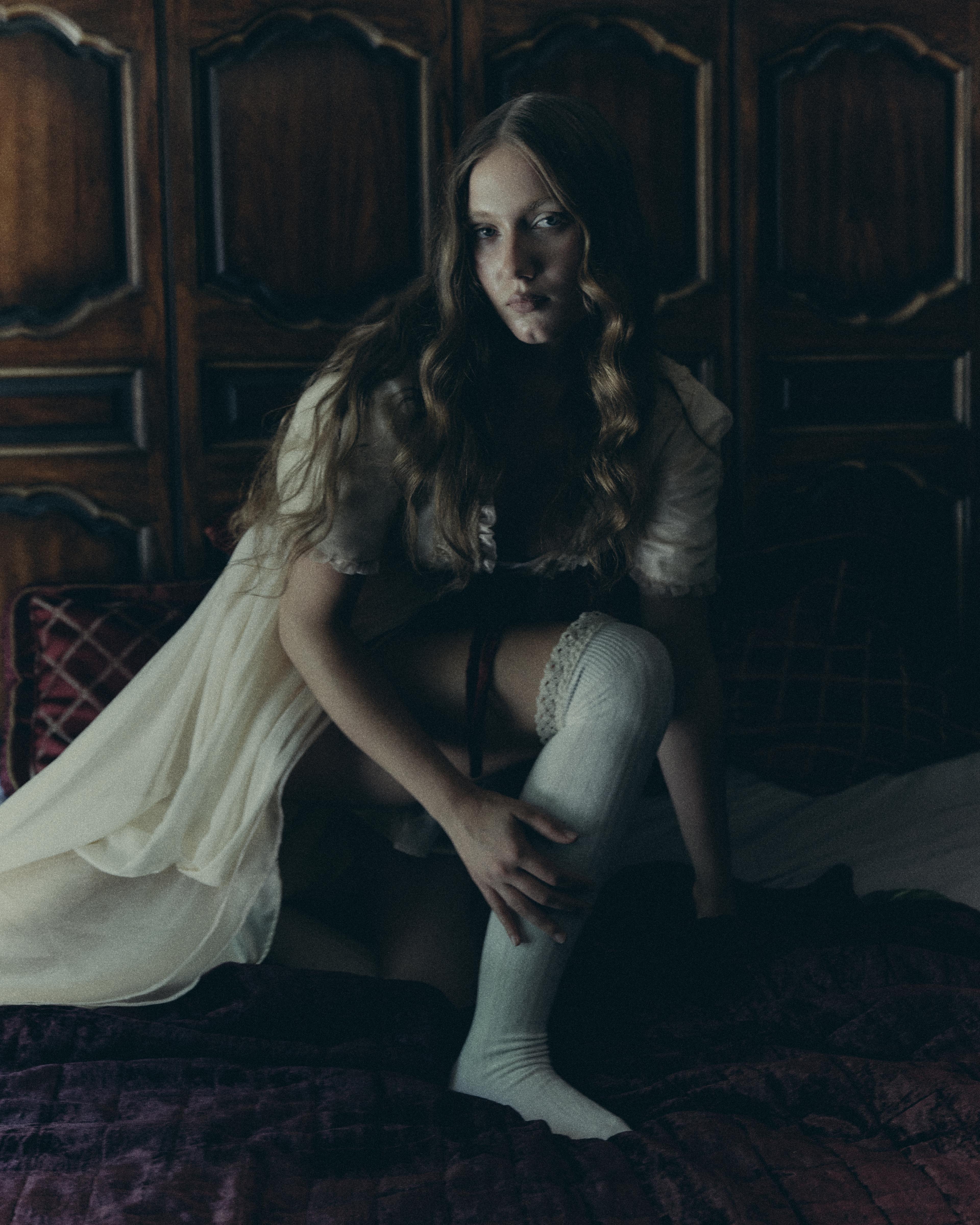 Girl wearing all white on a bed.