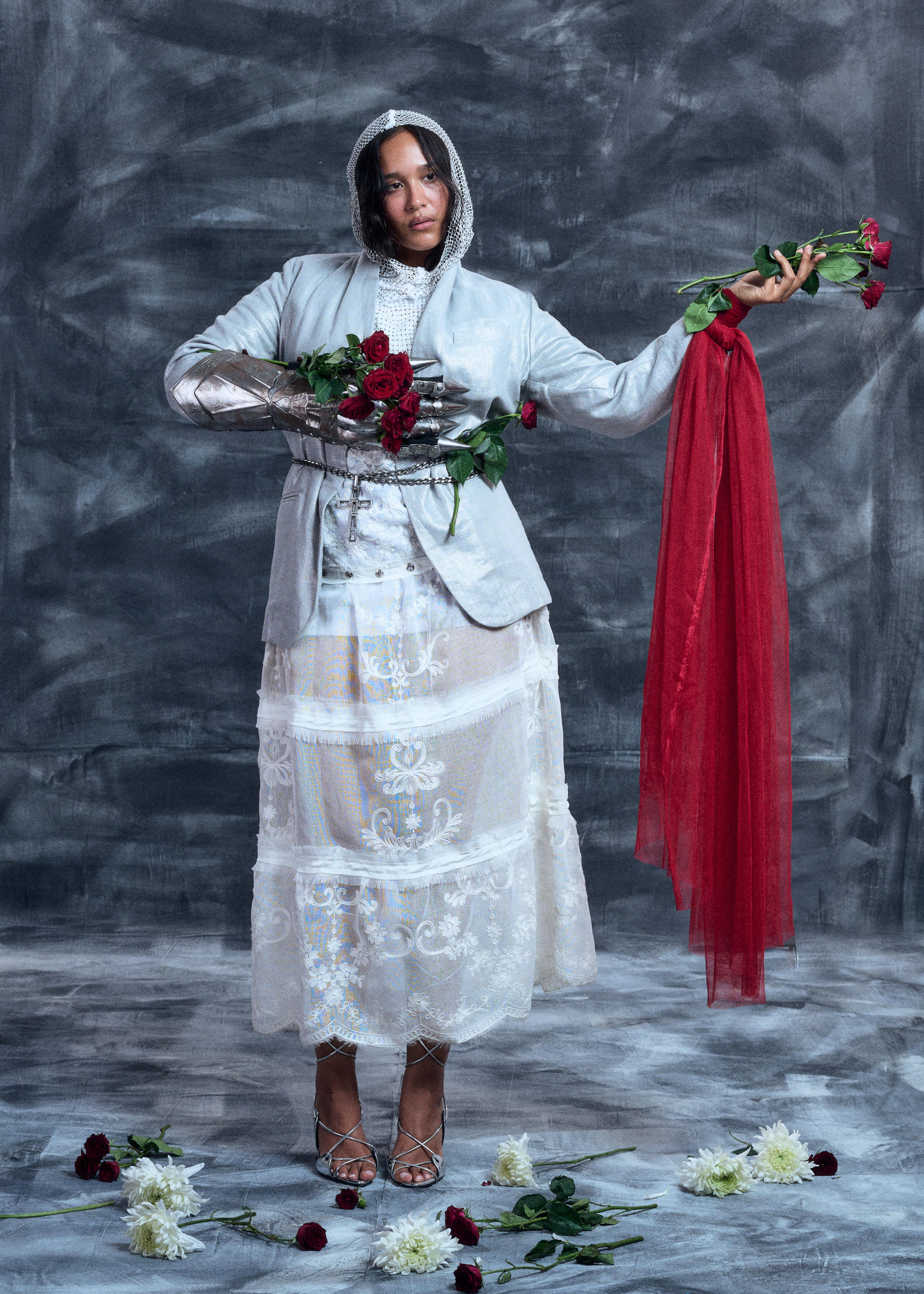 Girl wearing silver hooded look with metal armor gloves, red roses, and a red scarf on her hand.