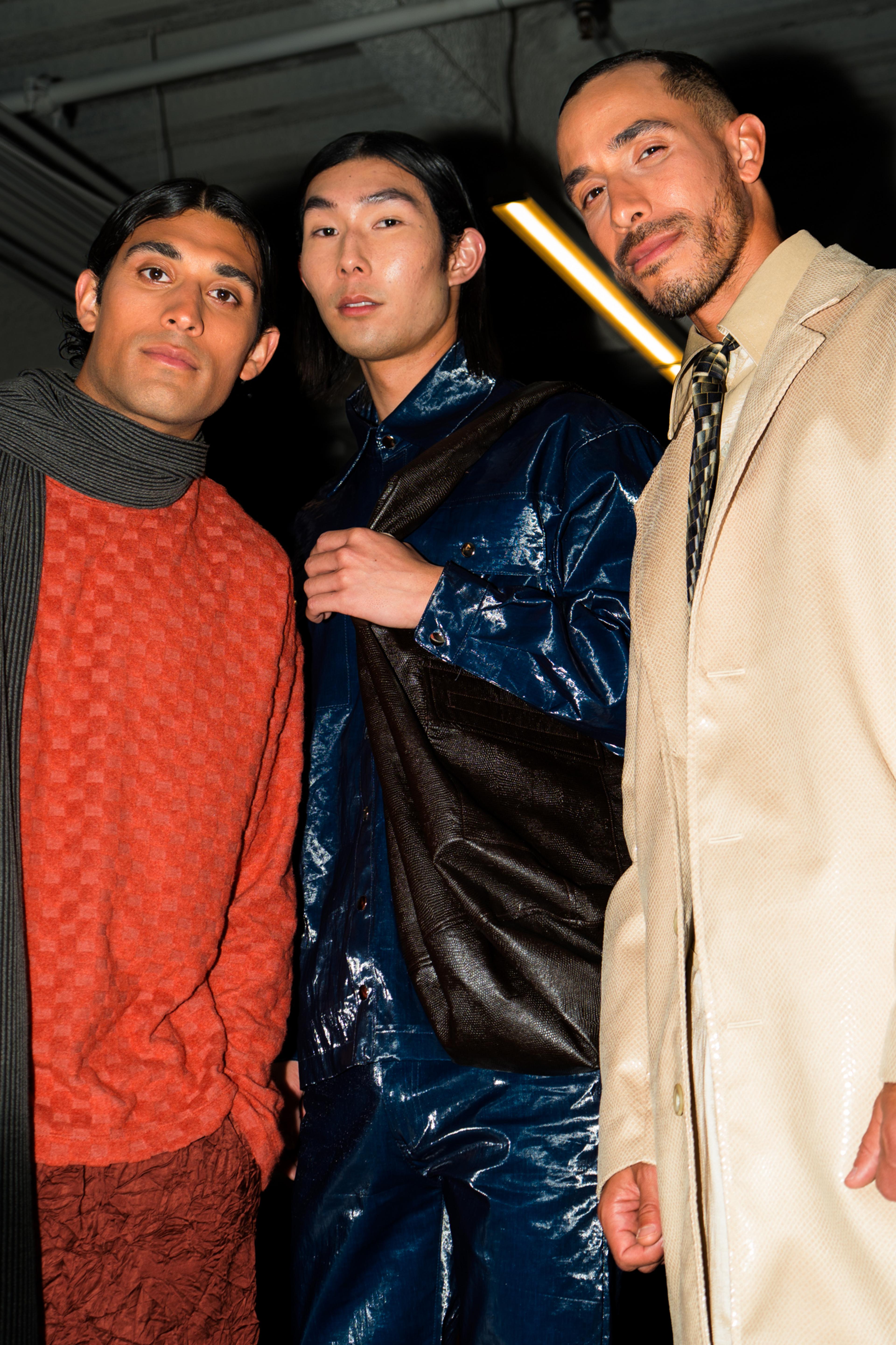 Three male models facing the camera close up wearing orange, blue, and tan.
