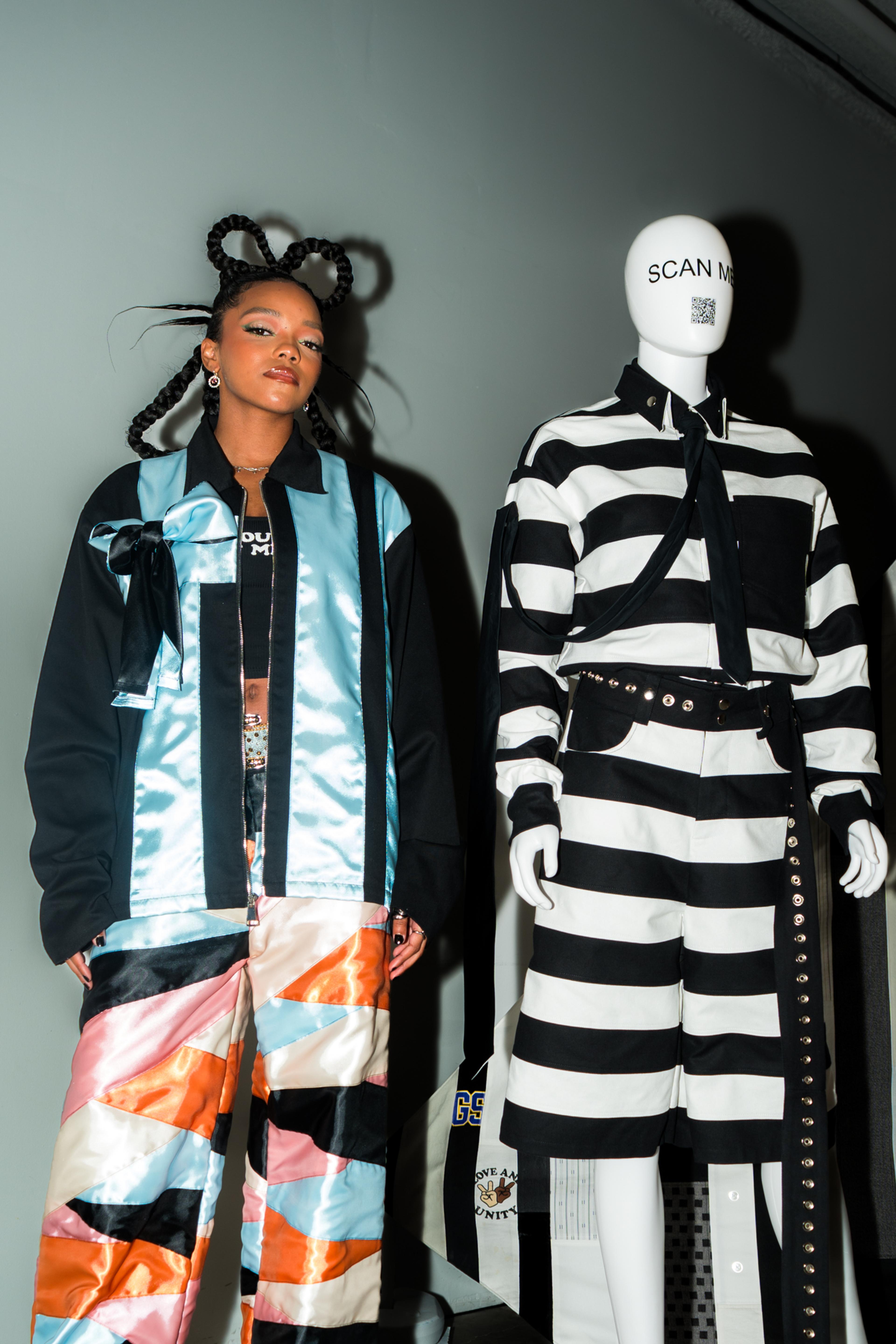 Regan Aliyah standing next to a mannequin in the gallery wearing a striped look.