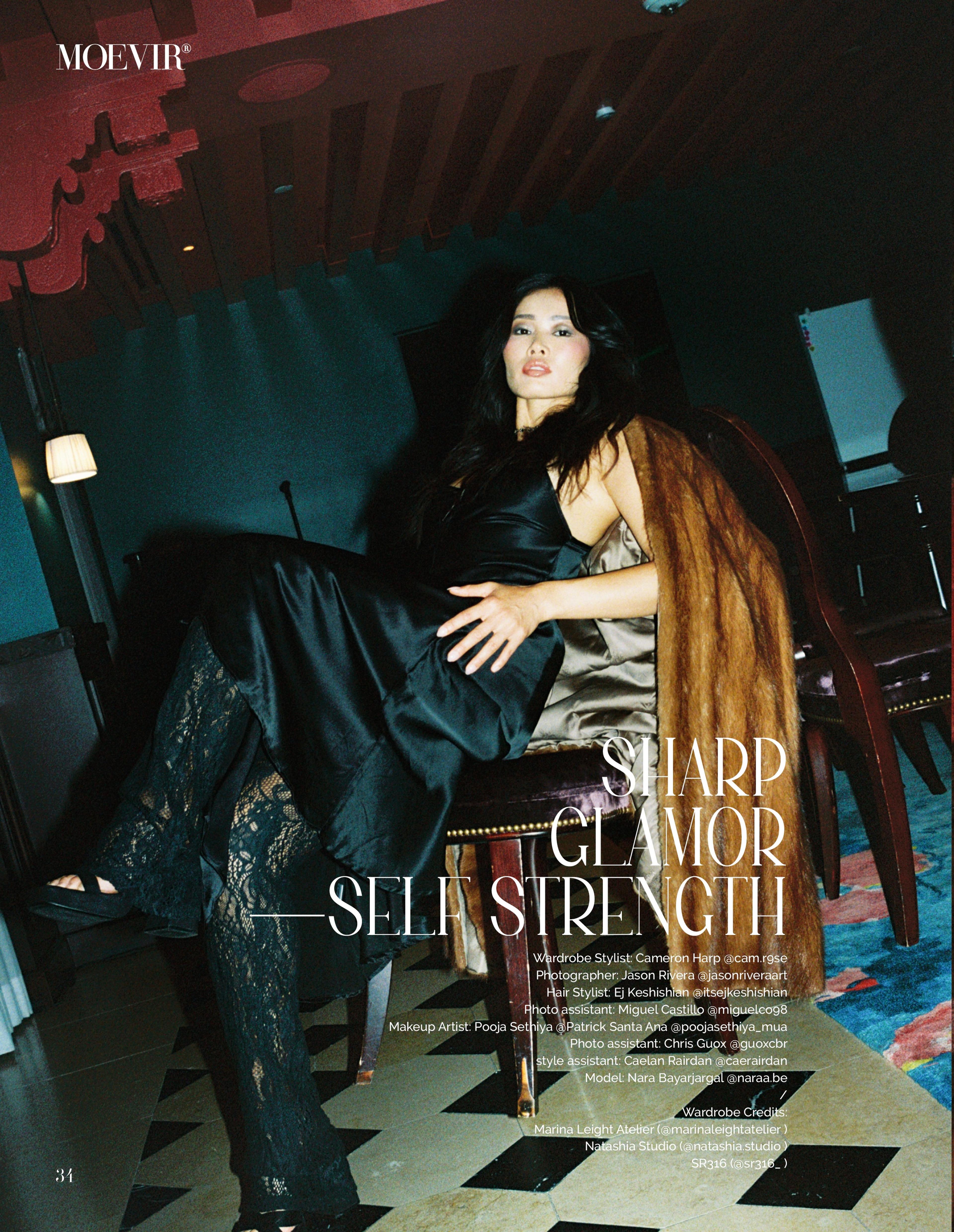 Model wearing black silk dress and black lace tights with a brown fur coat sitting in a chair.