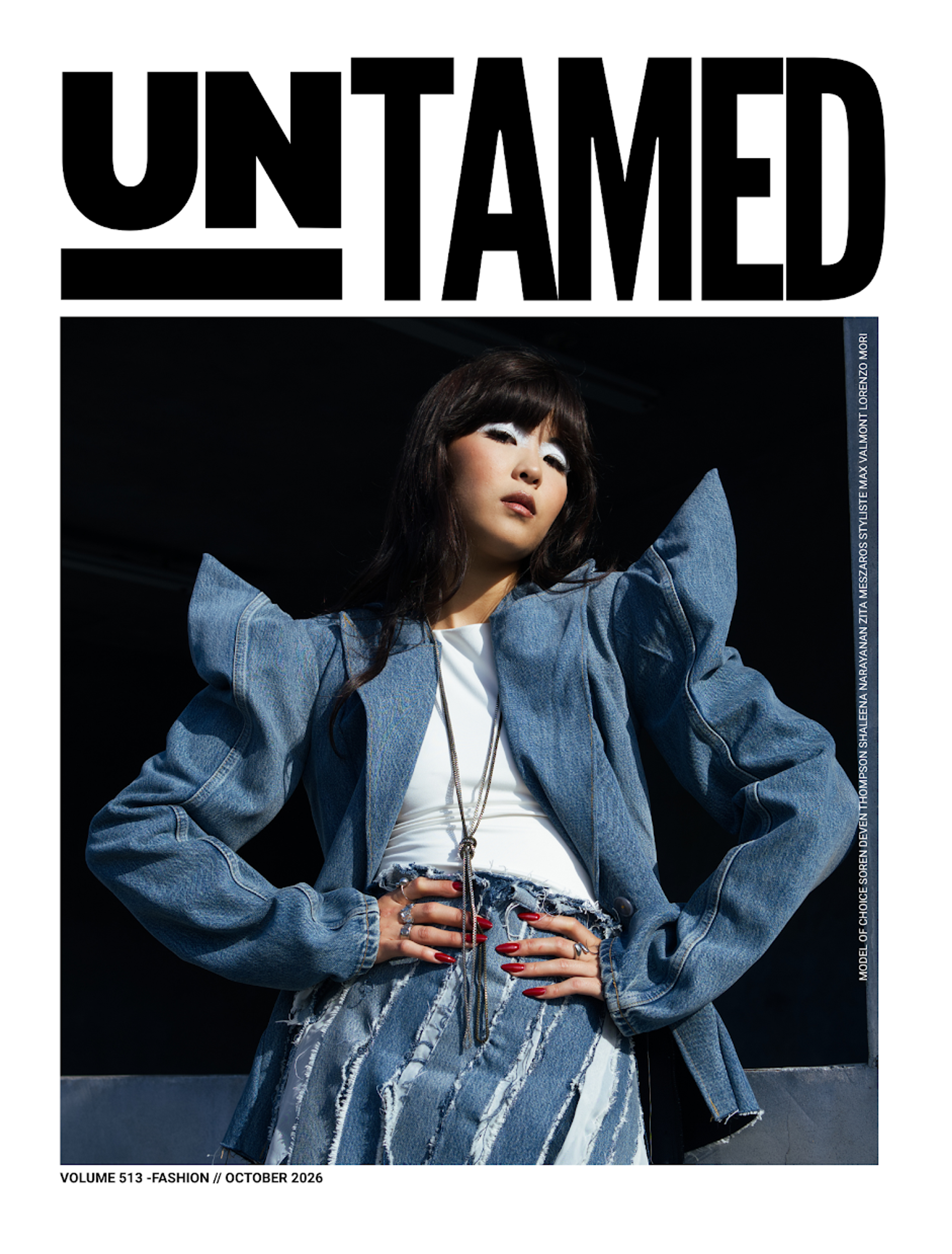 A girl wearing a pointed shoulder denim jacket with her hands on her hips and head tilted to one side.
