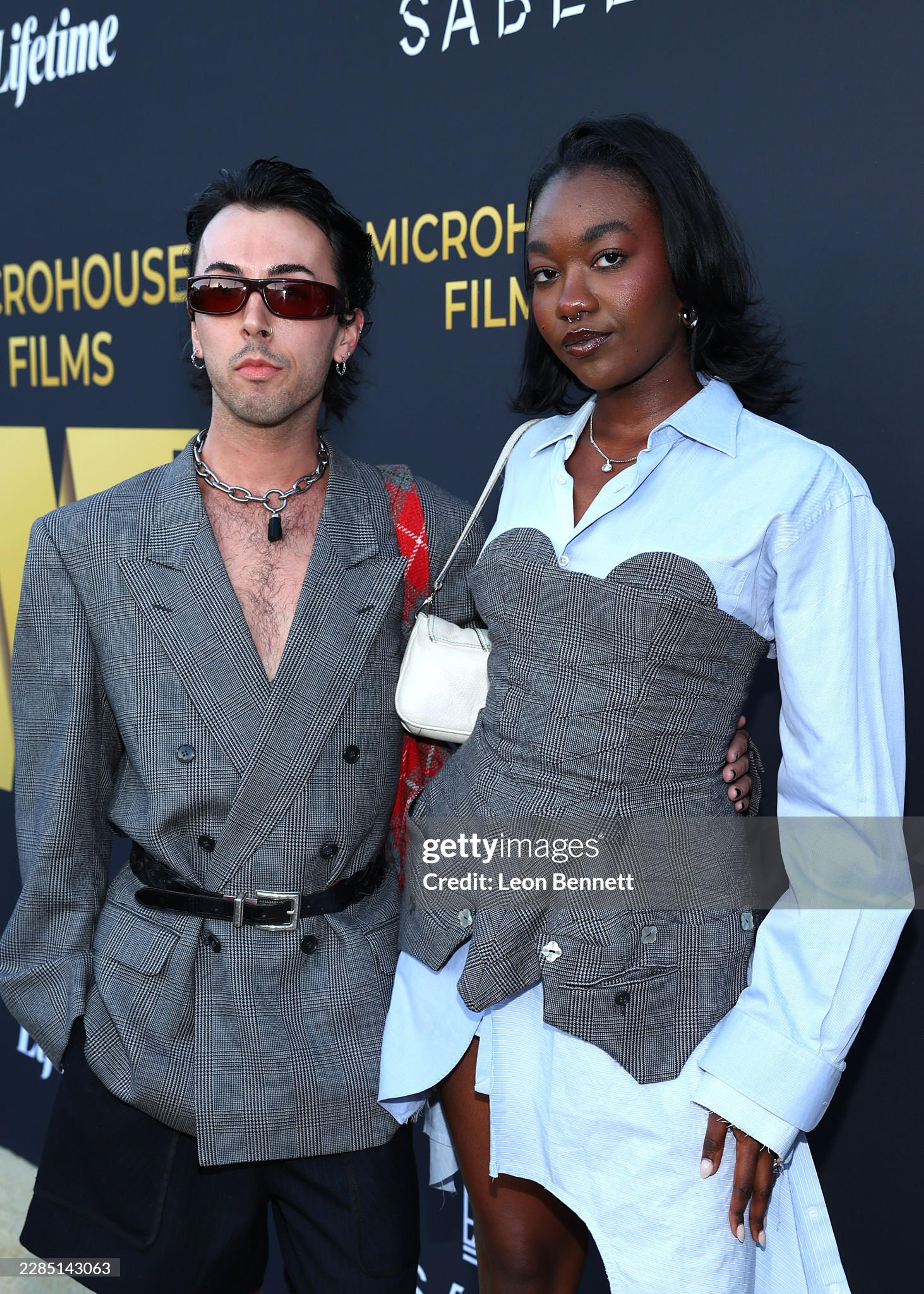 Two people wearing grey suiting on red capret for movie premier up close.