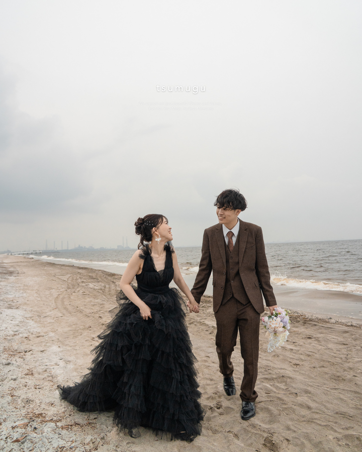 稲毛海浜公園の海辺を黒いドレスとスーツ姿で歩くふたり