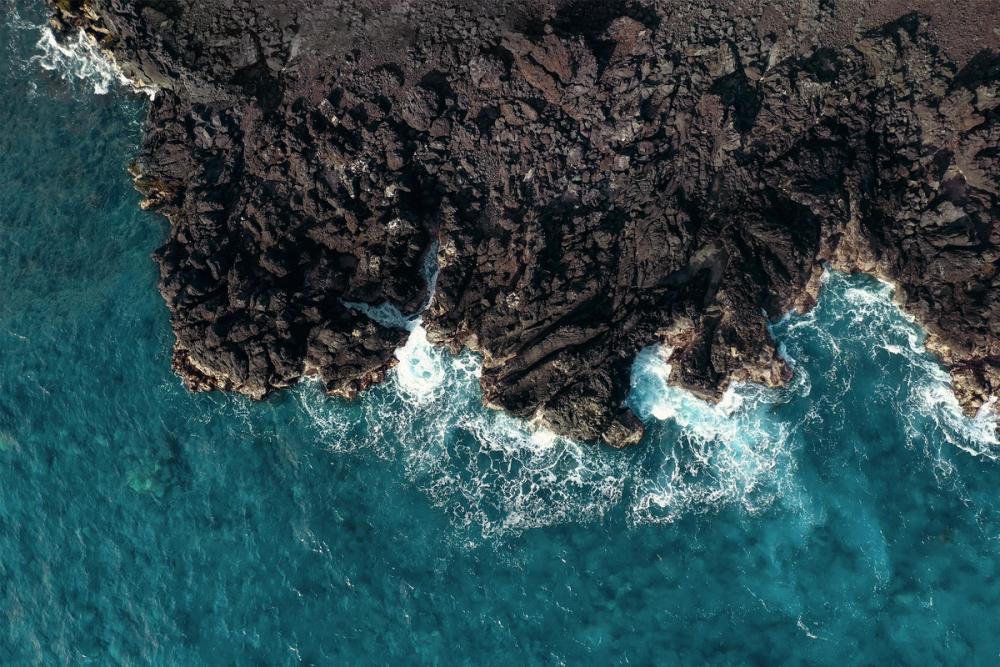 Ocean waves crashing into sharp lava rock