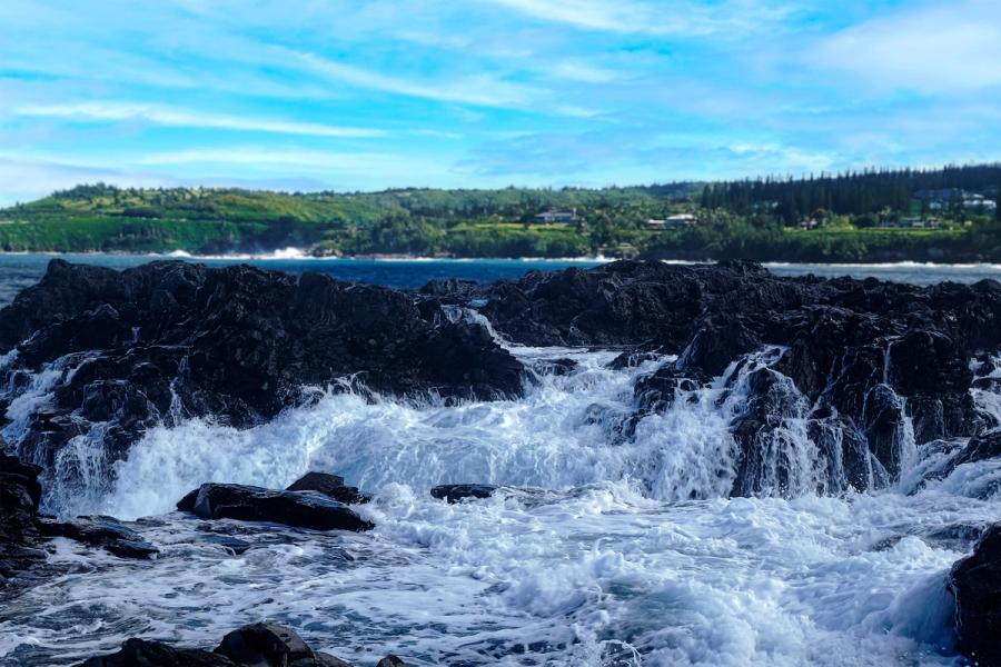 Wave crashing over lava rocks creating a waterfall