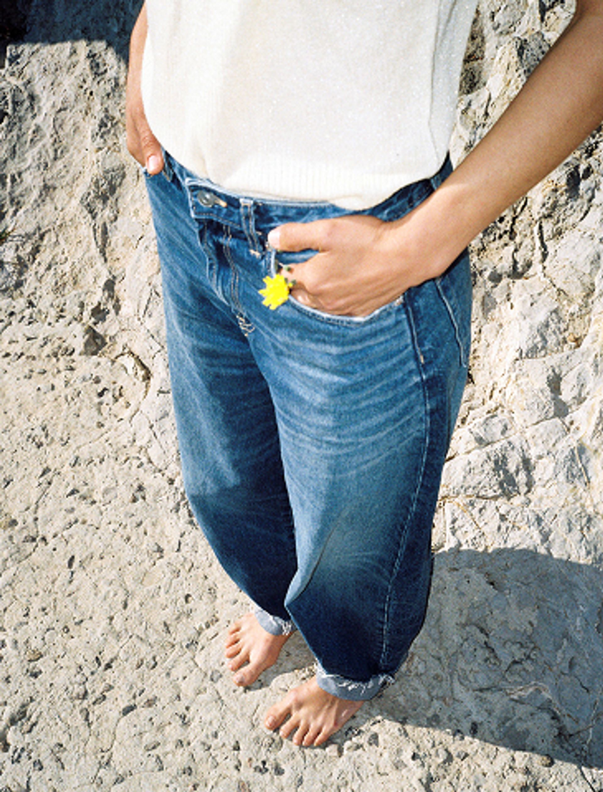 A woman with a daisy tucked into her denim jeans