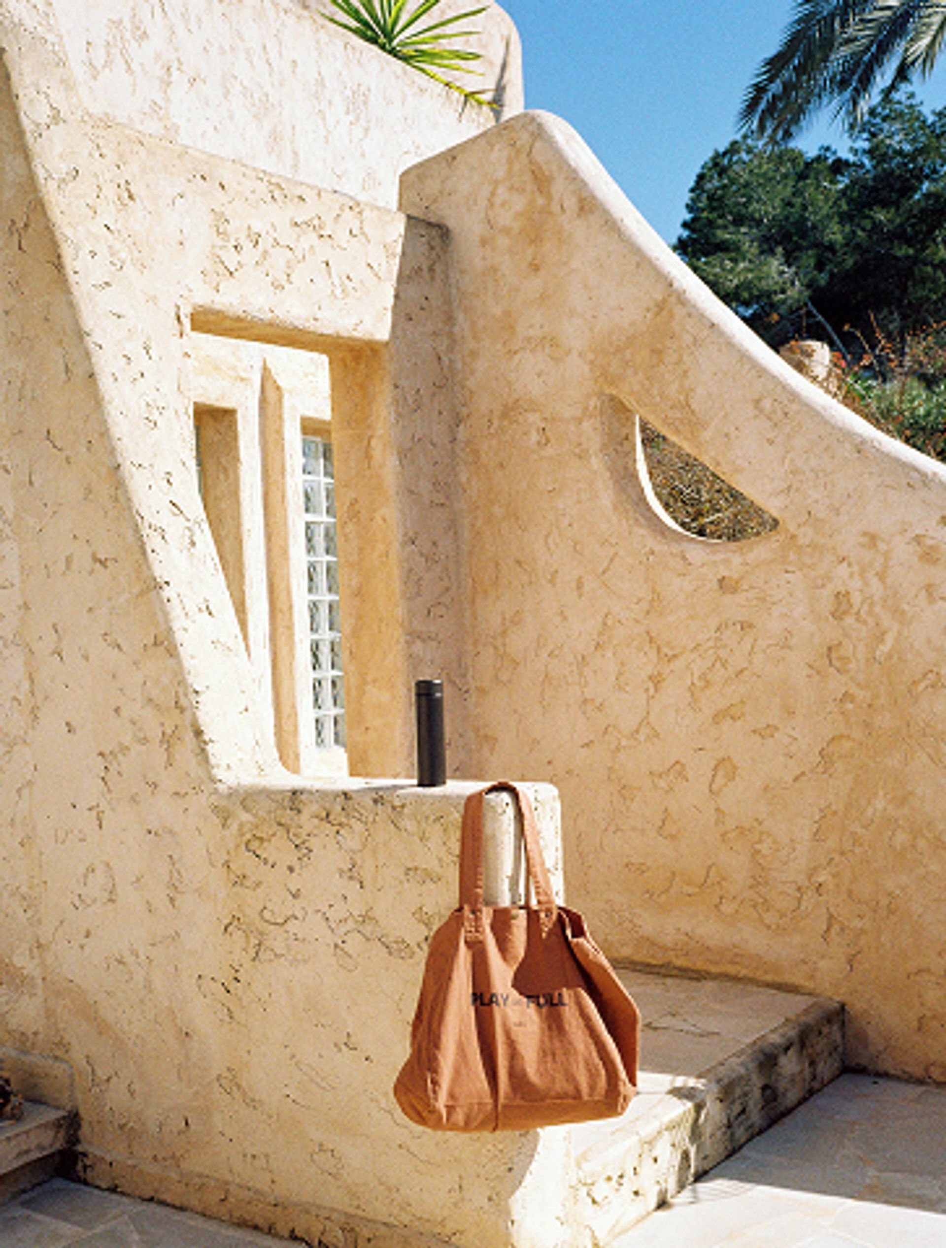 A leather bag hanging against a sculptural Ibiza facade