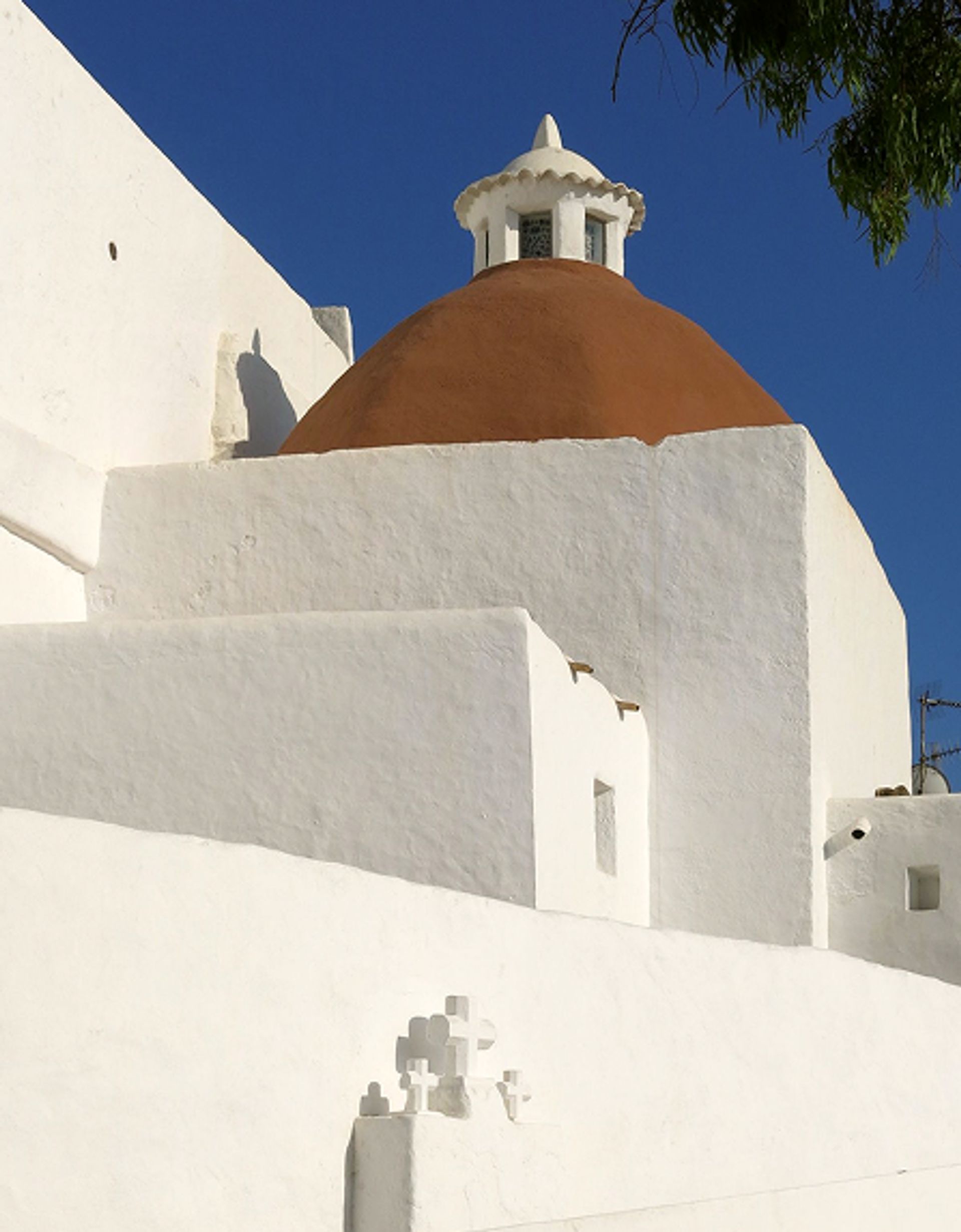 A terracotta-domed chapel roof against a blue sky