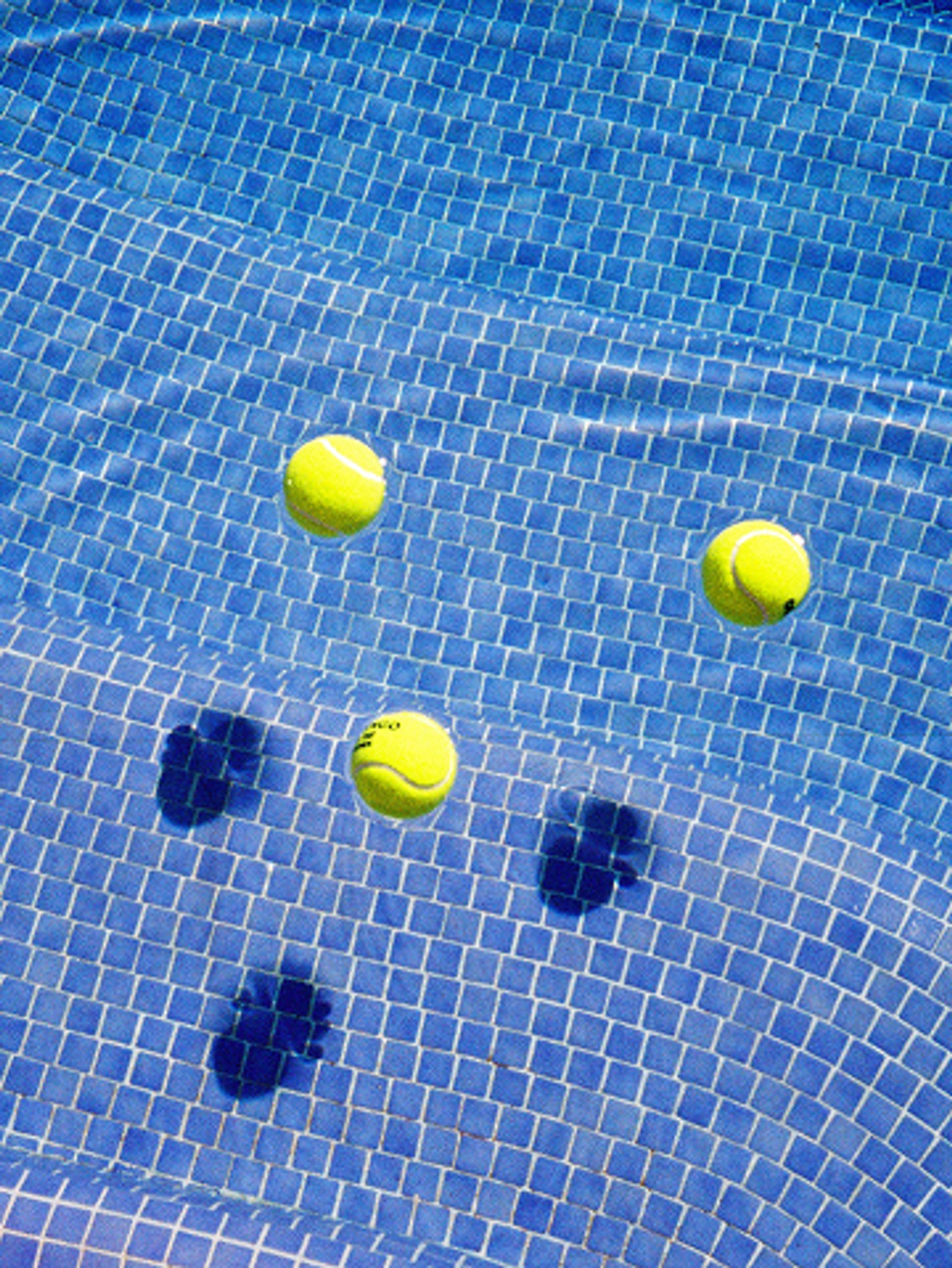 Tennis balls floating in a tiled pool