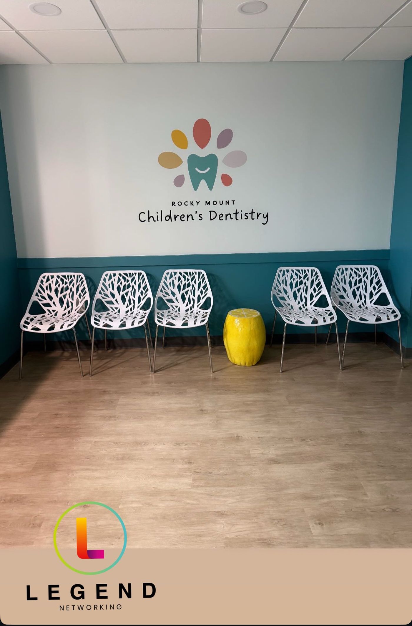 Waiting room with practice logo on the wall and white chairs at Rocky Mount Children's Dentistry, Rocky Mount, NC