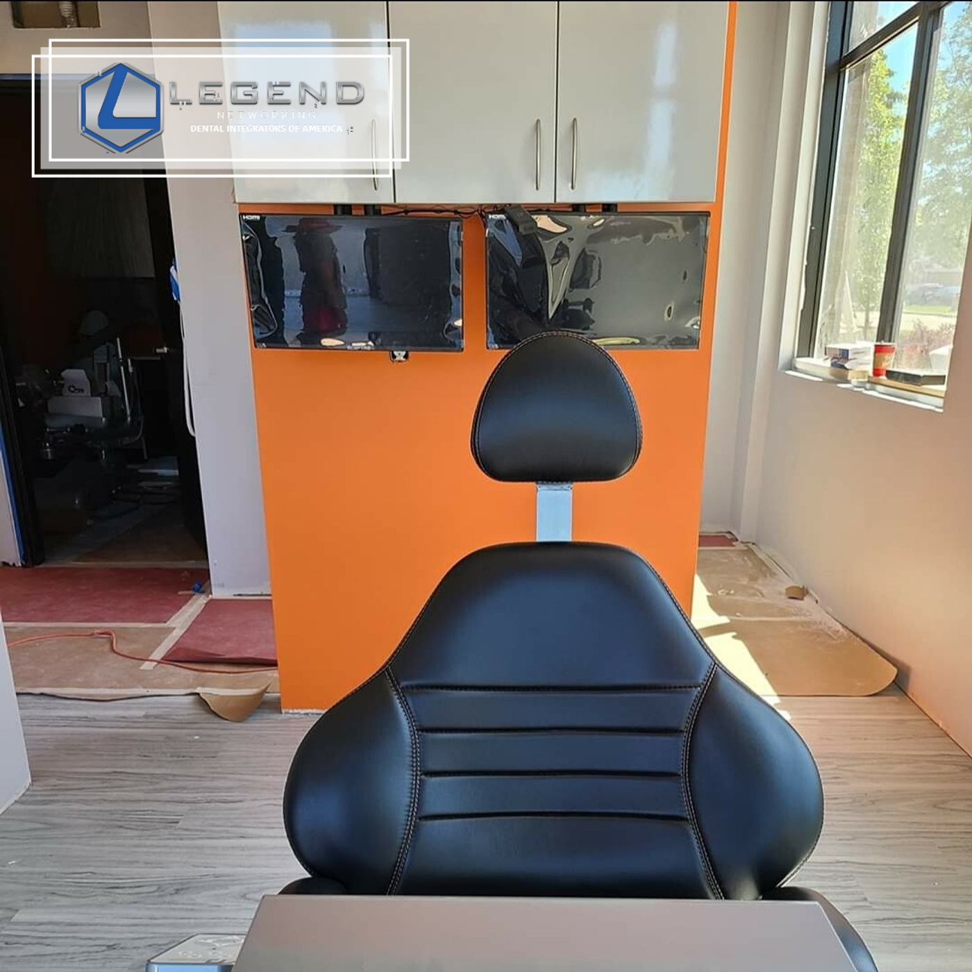 Dental chair in a treatment room with orange accent wall and monitors at Fenton Smiles, Fenton, MI