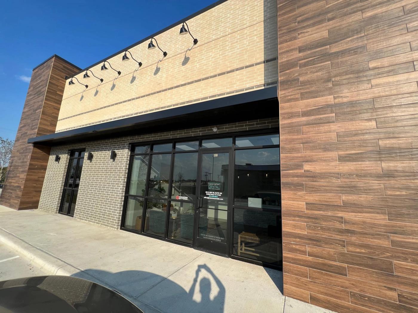 Brick and wood-clad storefront with glass entrance doors at Stone Canyon Dental in Sunnyvale, TX