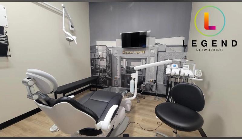 Treatment room with dental chair, wall-mounted TV and city-skyline wall mural at Kashmere Dental Studios, Converse, TX