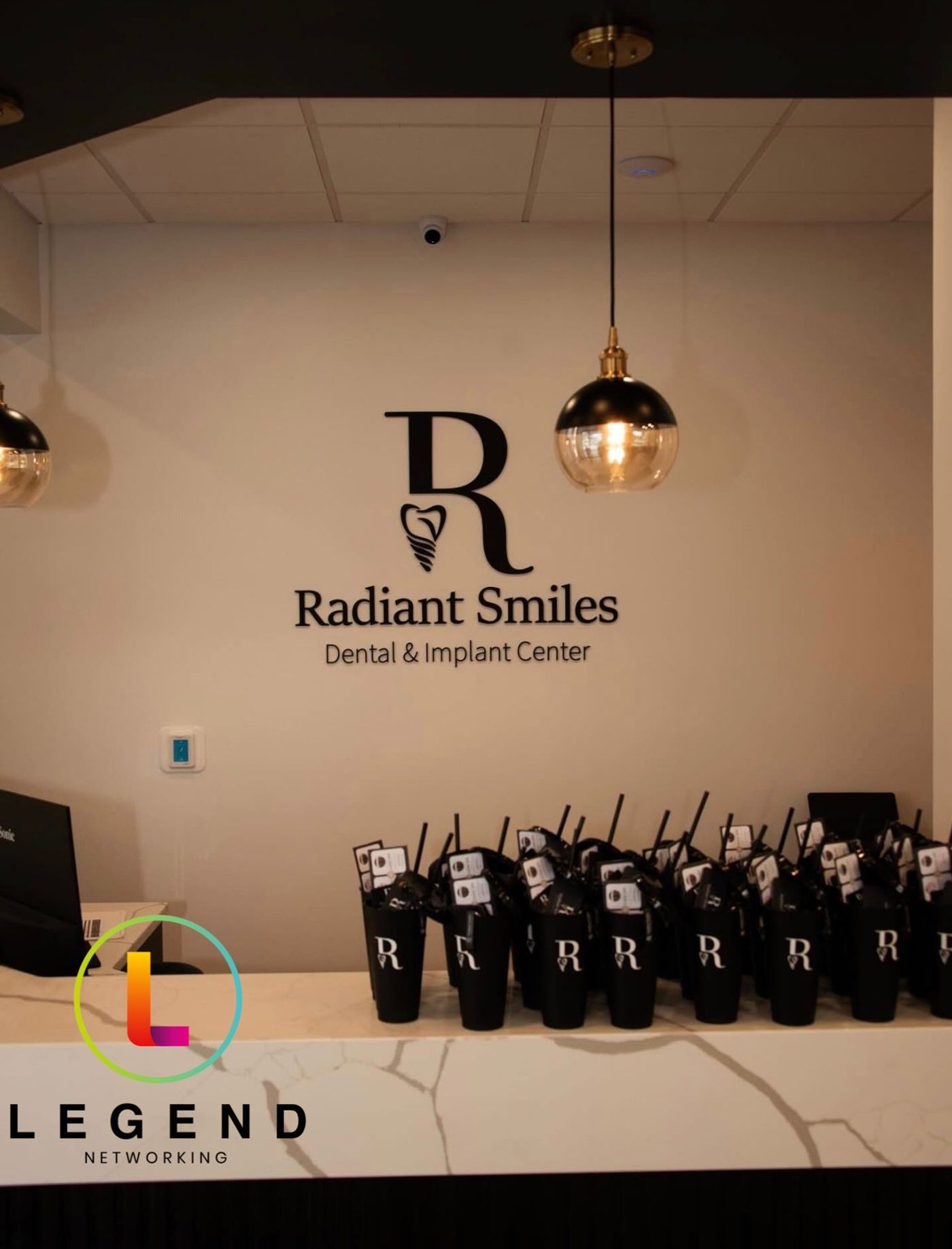 Reception wall with the Radiant Smiles logo and branded tumblers at Radiant Smiles Dental & Implant Center, Pace, FL