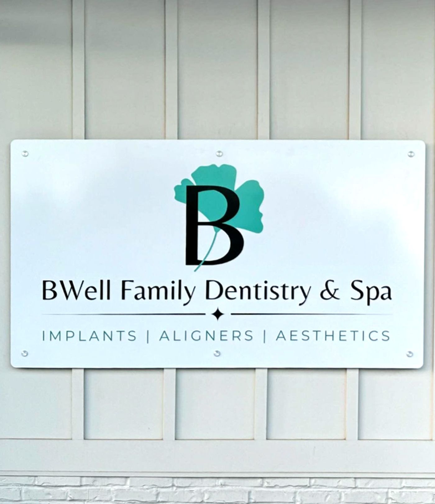 Wall sign for BWell Family Dentistry & Spa listing implants, aligners and aesthetics, Simpsonville, SC