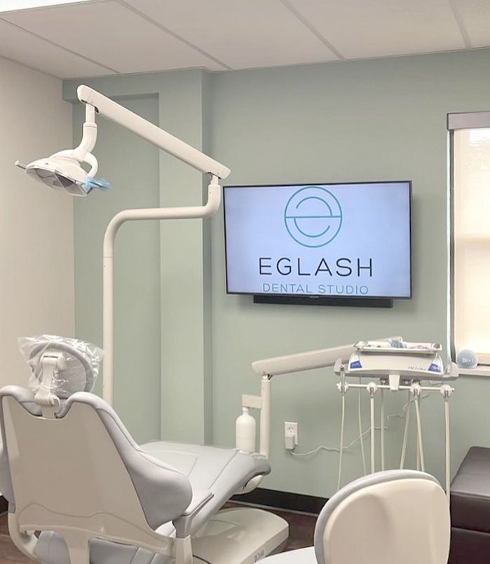 Treatment room with dental chair and a wall-mounted screen showing the Eglash Dental Studio logo in Pittsburgh, PA