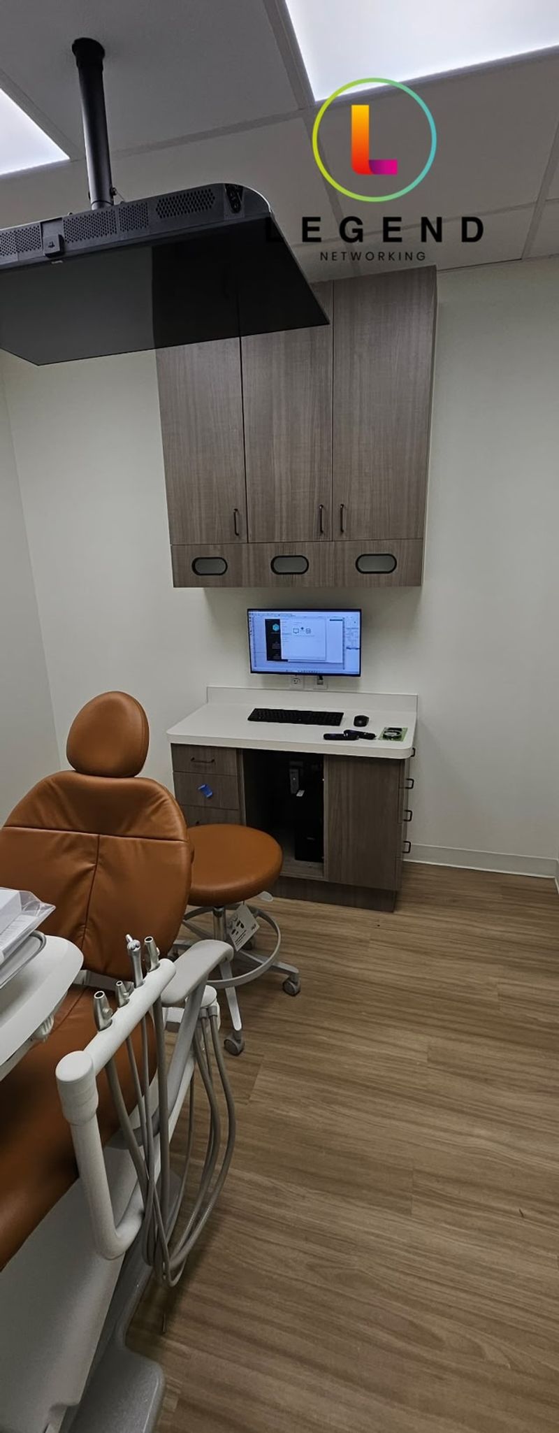 Operatory with dental chair, ceiling-mounted display and workstation at Gainesville Dental in Gainesville