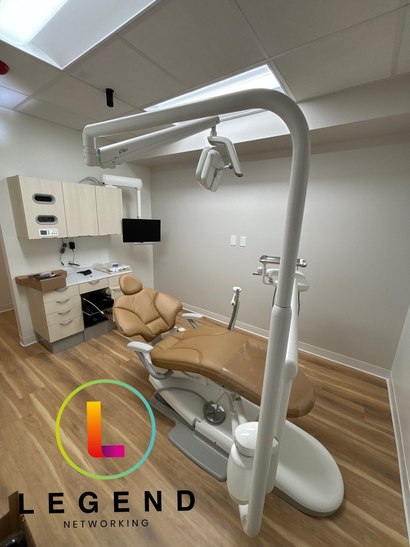 Treatment room with a dental chair and wall-mounted monitor at Heart of Hingham Dental Aesthetics