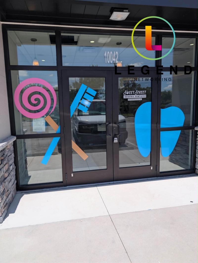 Entrance doors with lollipop, toothbrush and tooth window graphics at Sweet Street Pediatric Dentistry of Parrish