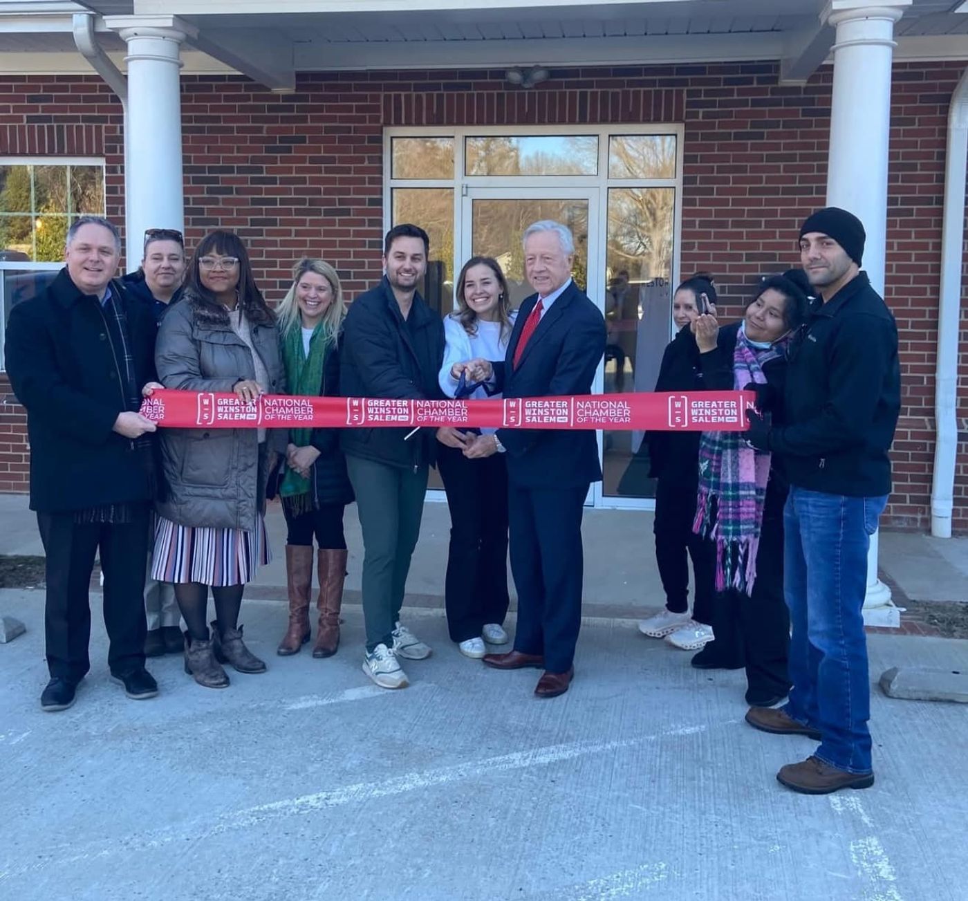 Ribbon-cutting with the team outside the brick office of Restoration Dental in Winston-Salem, NC