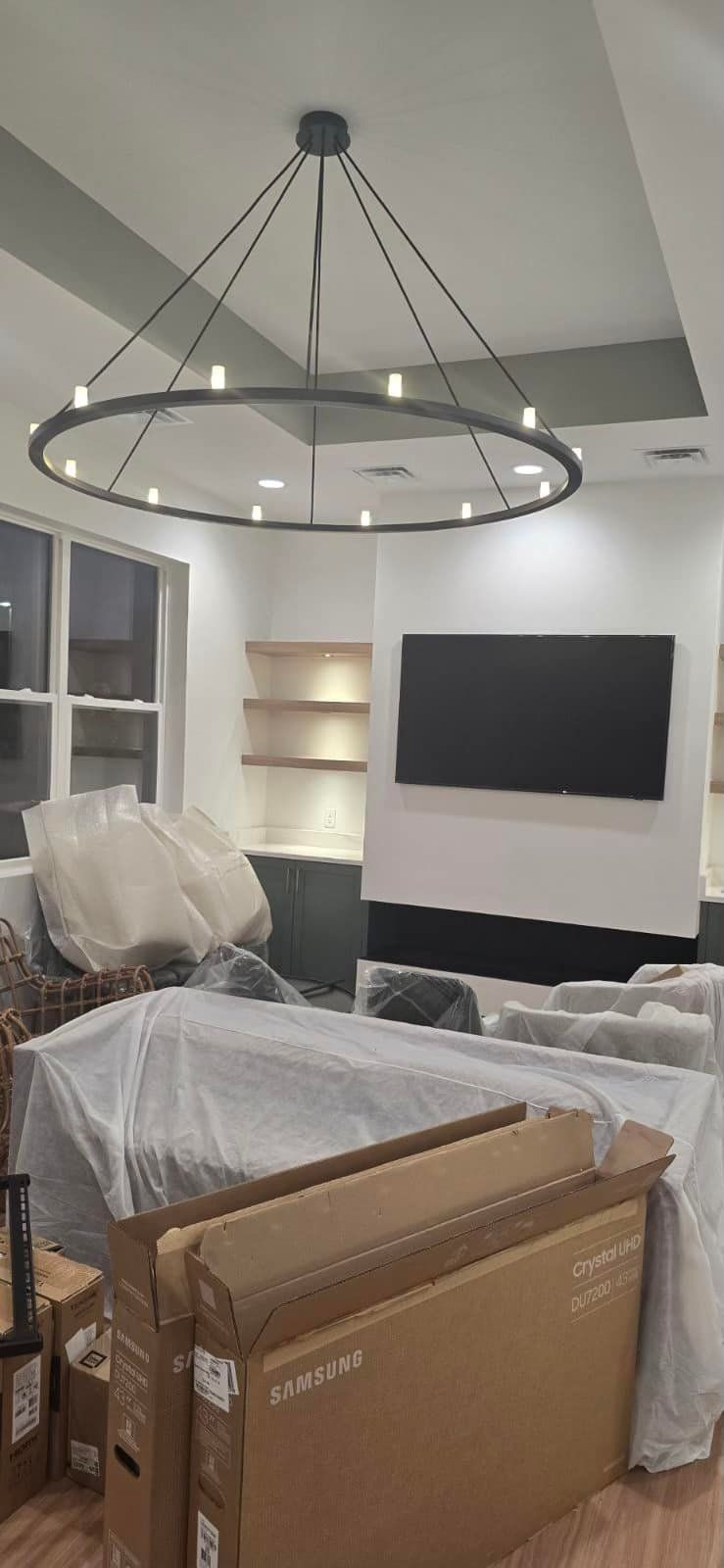 Room with a ring chandelier, wall-mounted TV and shelving at Rosebud Dental & Wellness in Gahanna