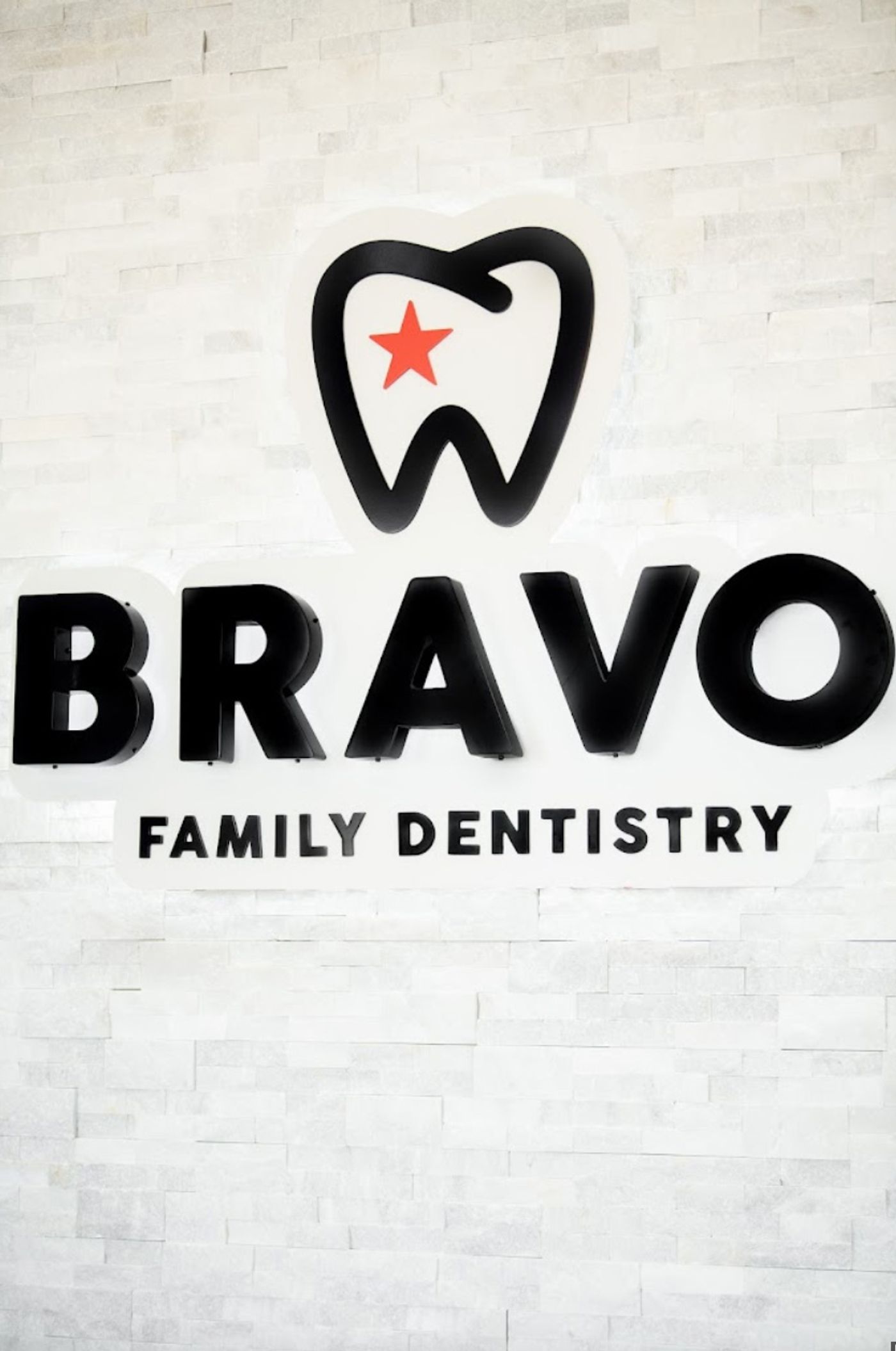 Bravo Family Dentistry logo sign on a white stone wall in Kyle, TX