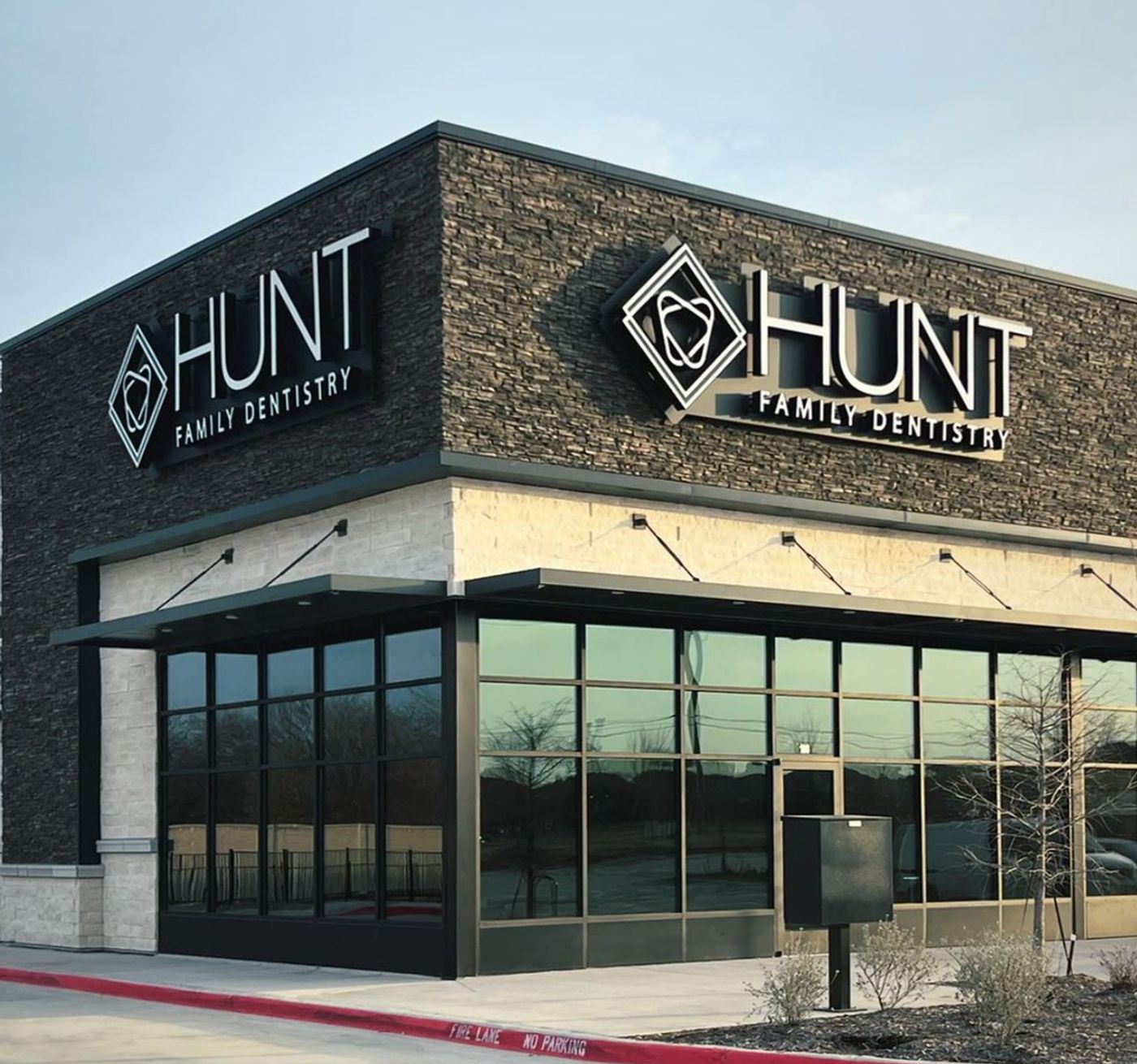 Stone storefront with the Hunt Family Dentistry sign above the entrance in Frisco, TX