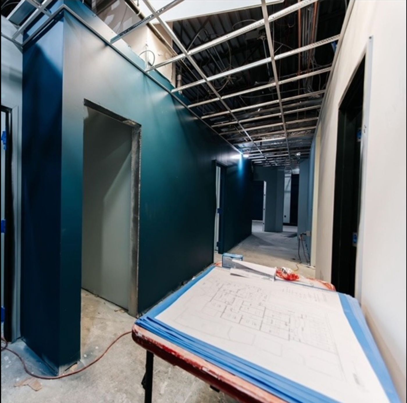 Construction hallway with floor plans laid on a table during the buildout of Hanover Pediatric Dentistry in Hanover, PA