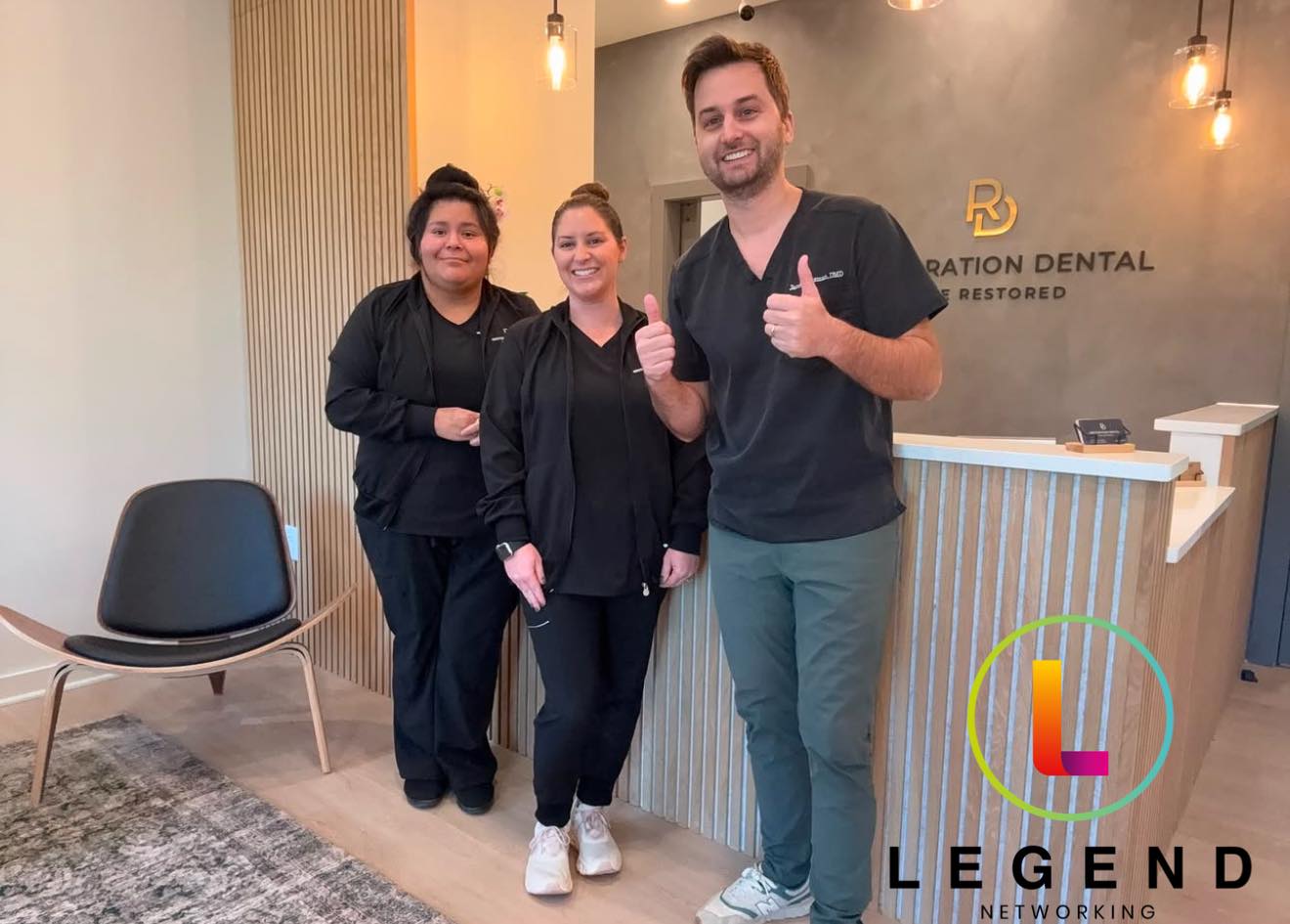 Team at the wood-slat front desk below the logo wall at Restoration Dental in Winston-Salem, NC