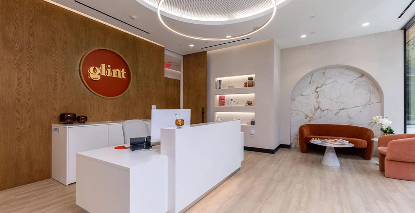 Reception desk and waiting area with the glint logo wall at Glint Dental Studio in Austin, TX