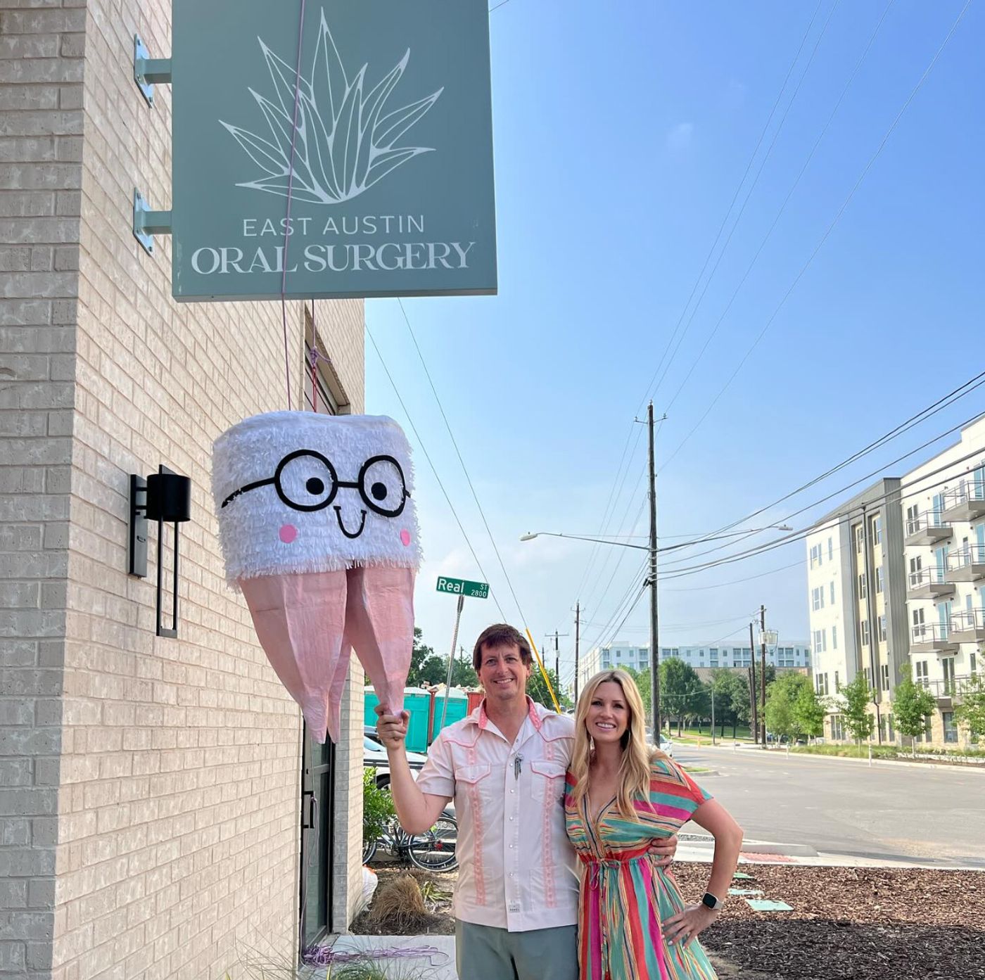 East Austin Oral Surgery hanging sign on the brick building with a tooth pinata in Austin, TX