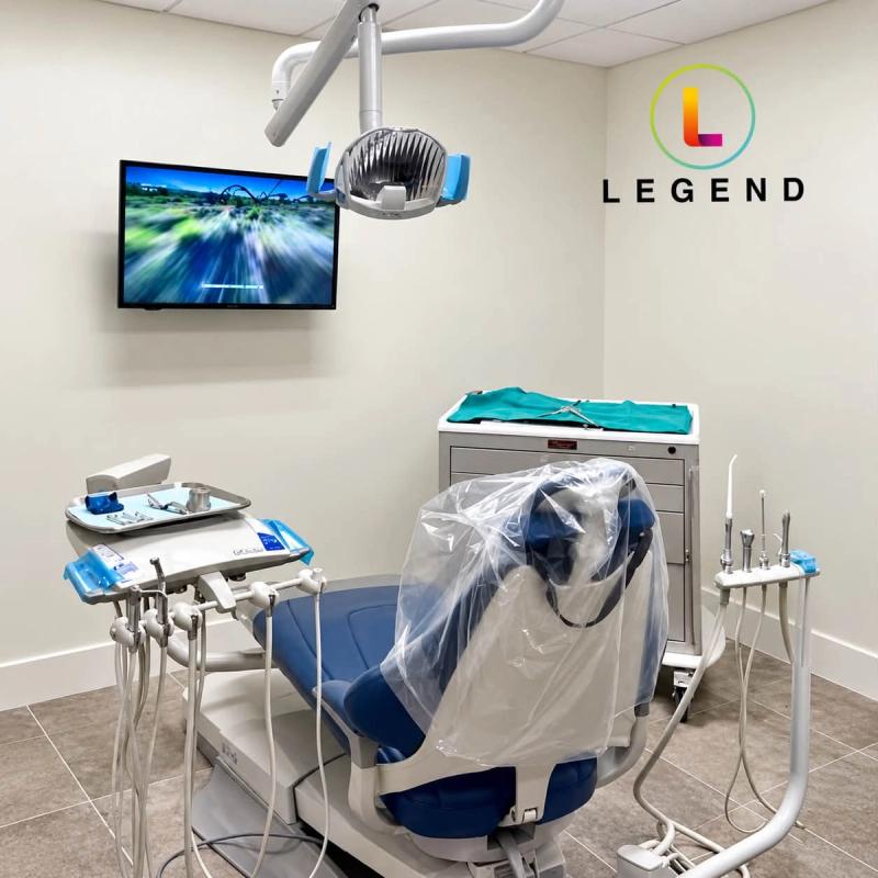 Treatment room with dental chair, delivery unit and wall-mounted screen at Venice Periodontics & Implant Dentistry, Venice, FL