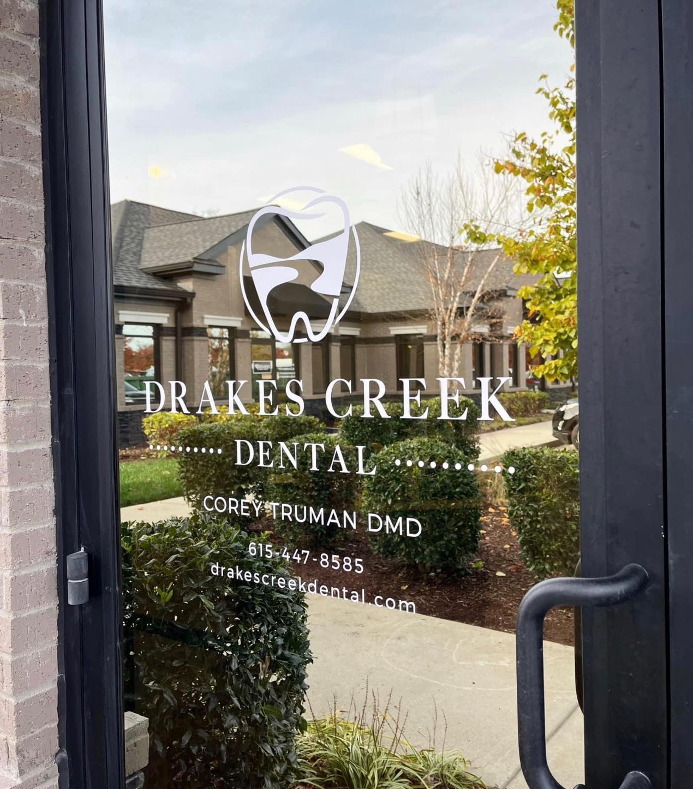 Glass entry door with the practice logo and doctor name at Drakes Creek Dental in Hendersonville, TN