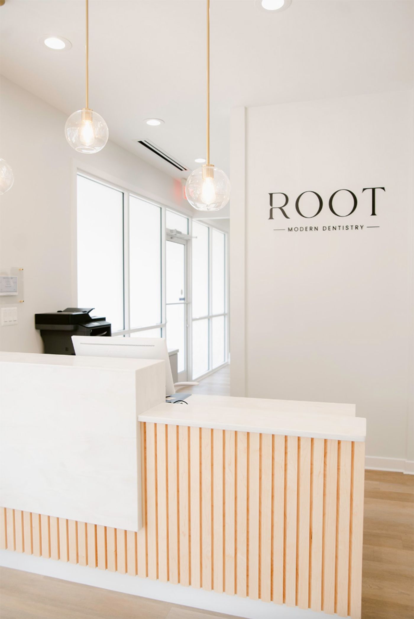 Front desk with wood-slat counter and Root wall sign at Root Modern Dentistry in Ashland, VA