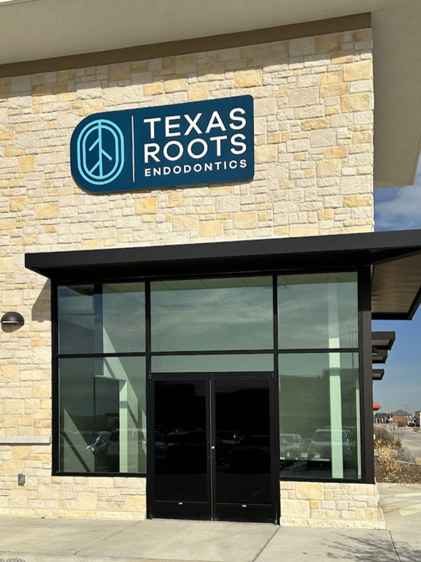 Stone storefront with the Texas Roots Endodontics sign above glass doors in Fort Worth, TX