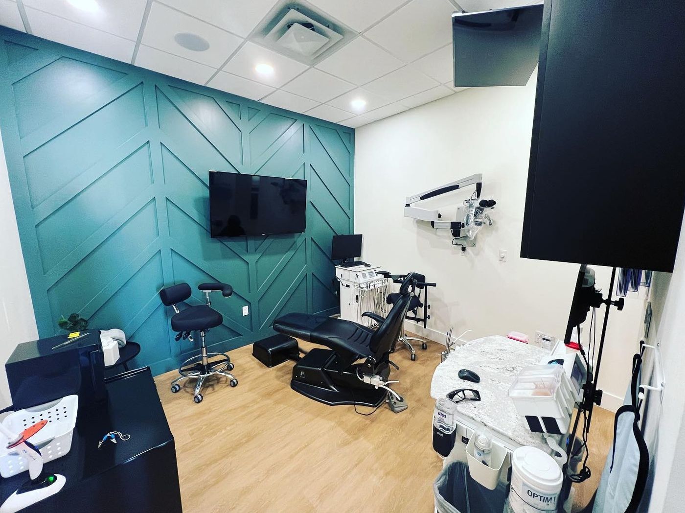Treatment room with dental chair, microscope and teal paneled wall at Leon River Endodontics, Temple, TX