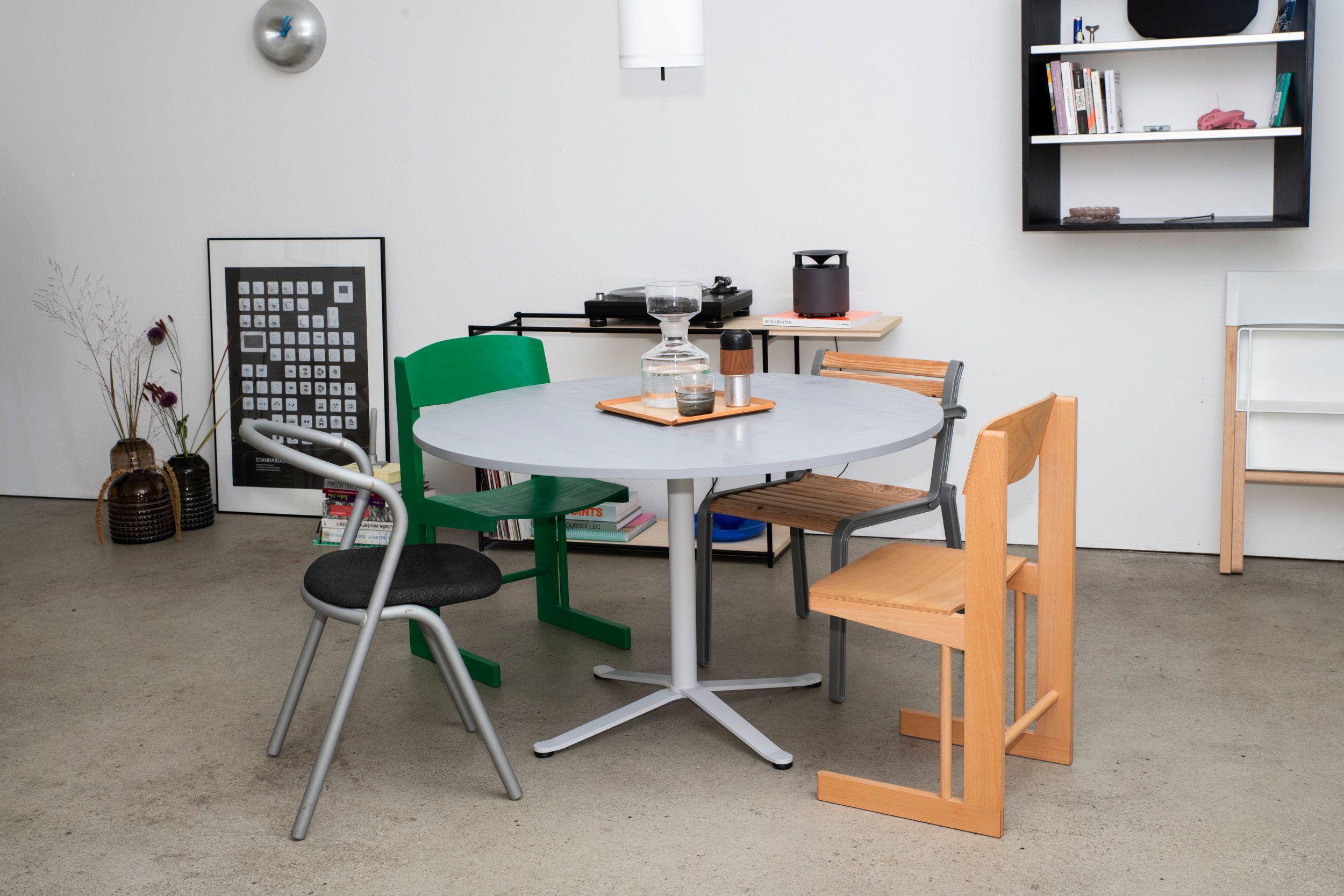 a room furnished with many different design pieces, chaits, table, shelves