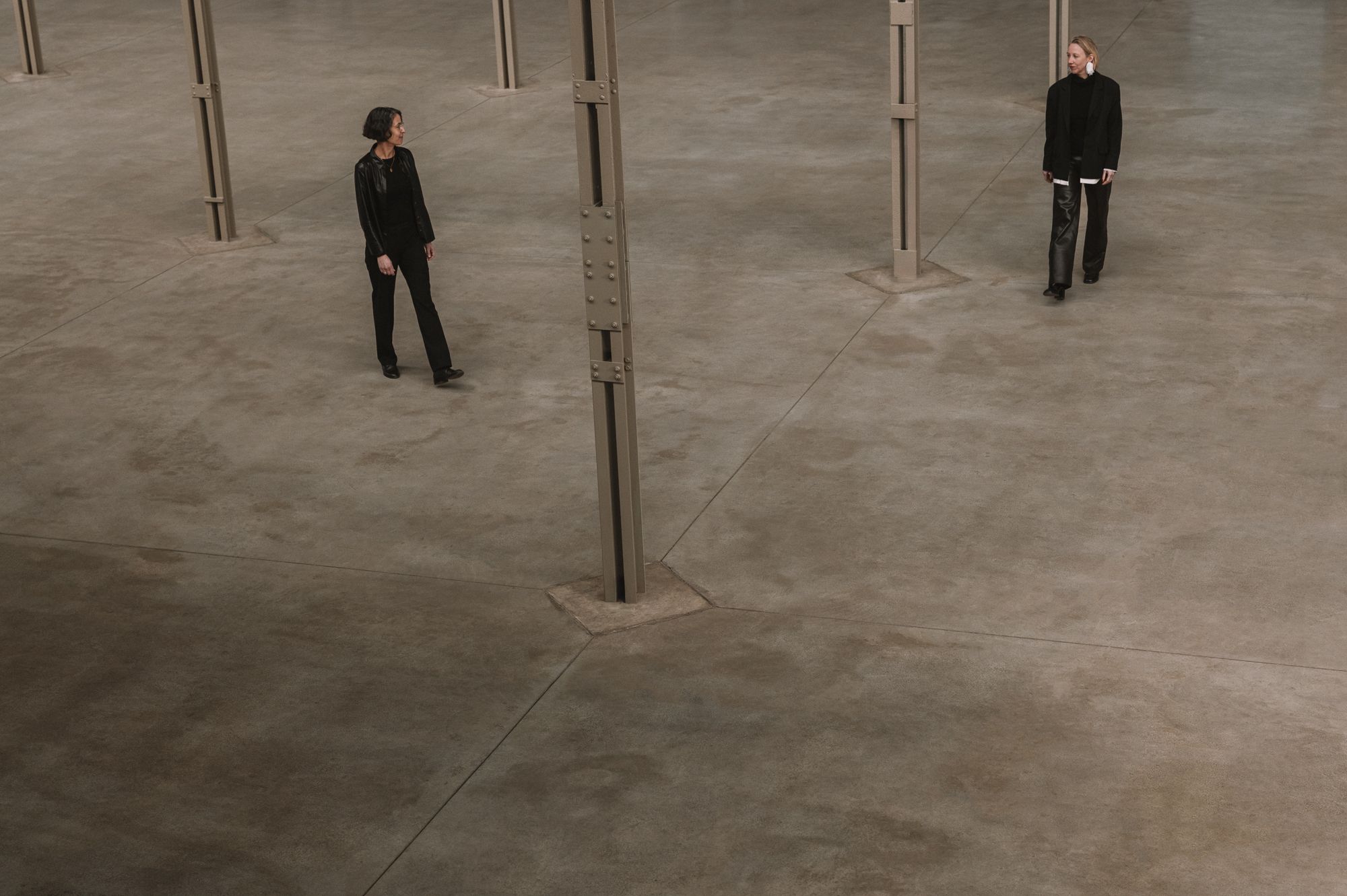 a big industrial space with two women looking at each other, dressed in black