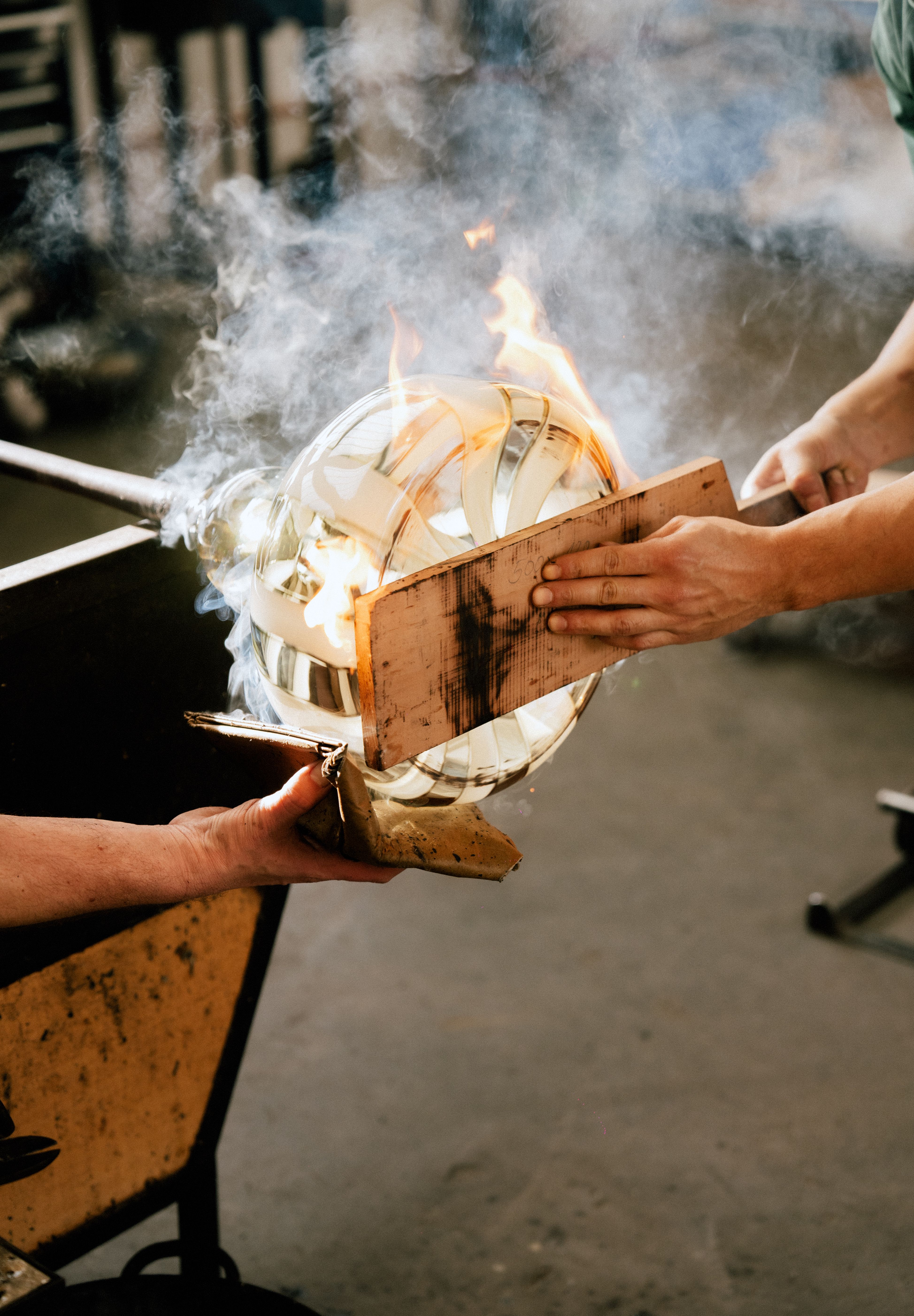 at a glass hotshop a vase being blown by two craftspeople