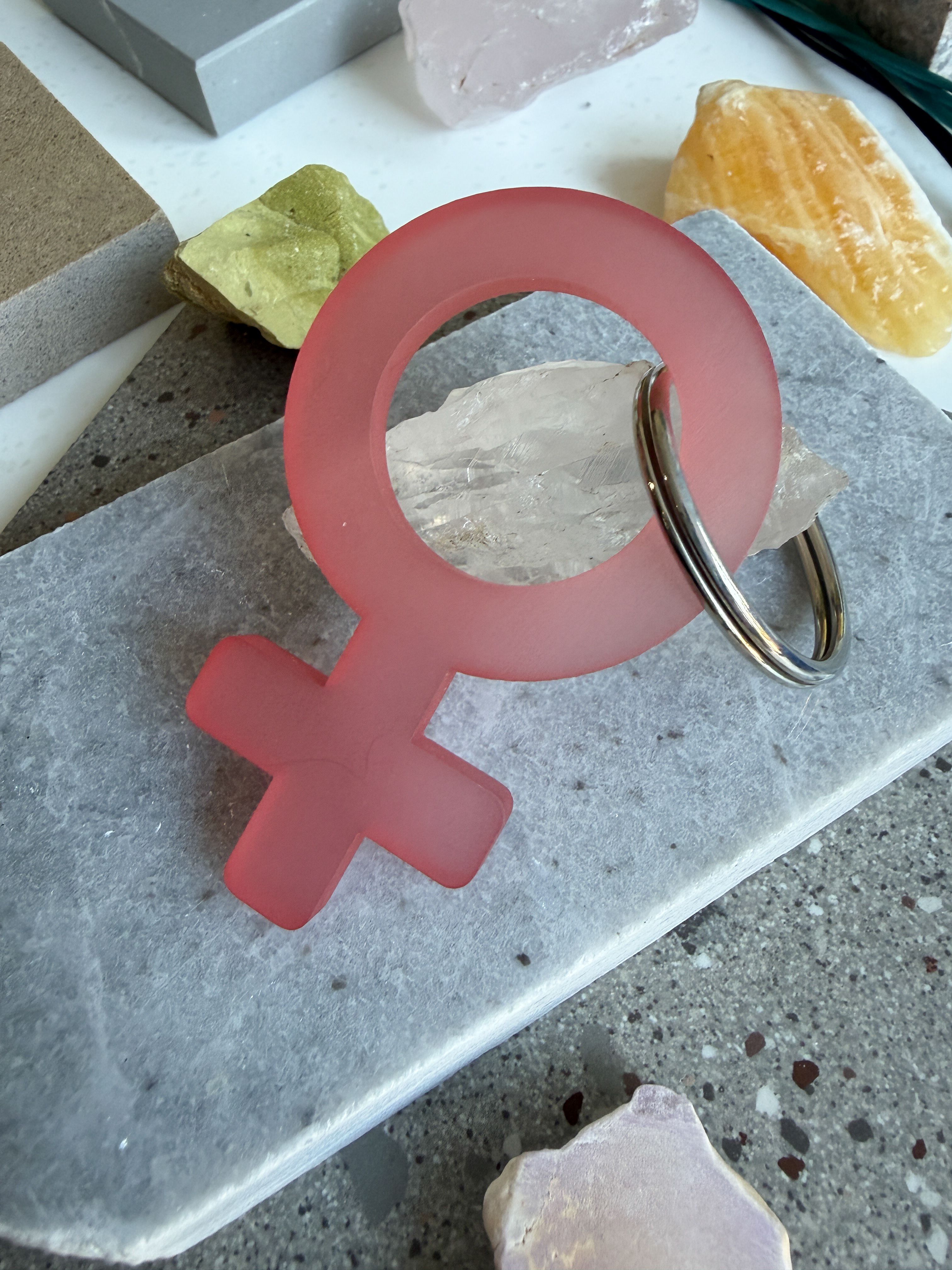 A frosted pink woman symbol keychain