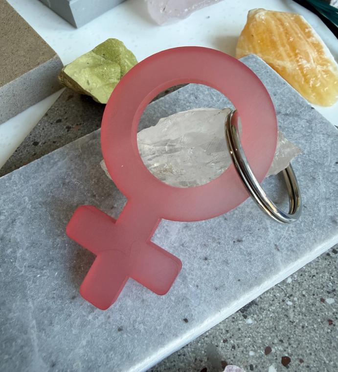 A frosted pink woman symbol keychain