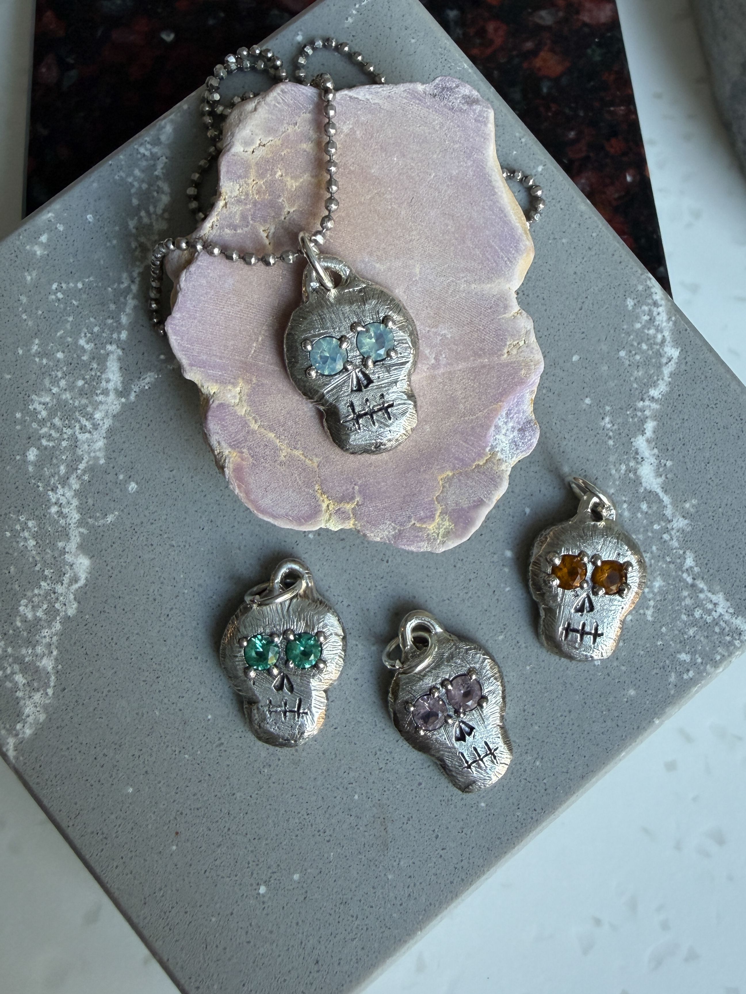 Skull pendant on chain with 3 additional skull pendants next to it