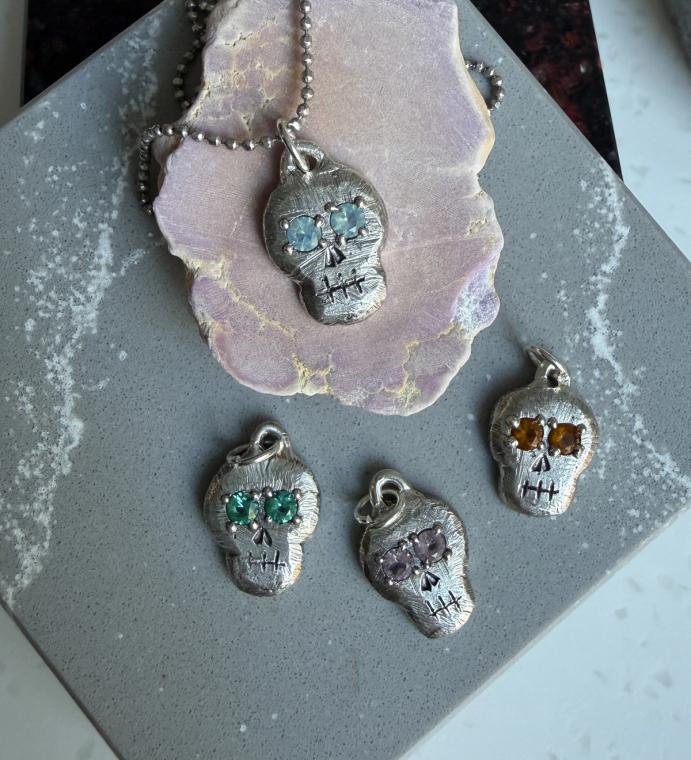 Skull pendant on chain with 3 additional skull pendants next to it