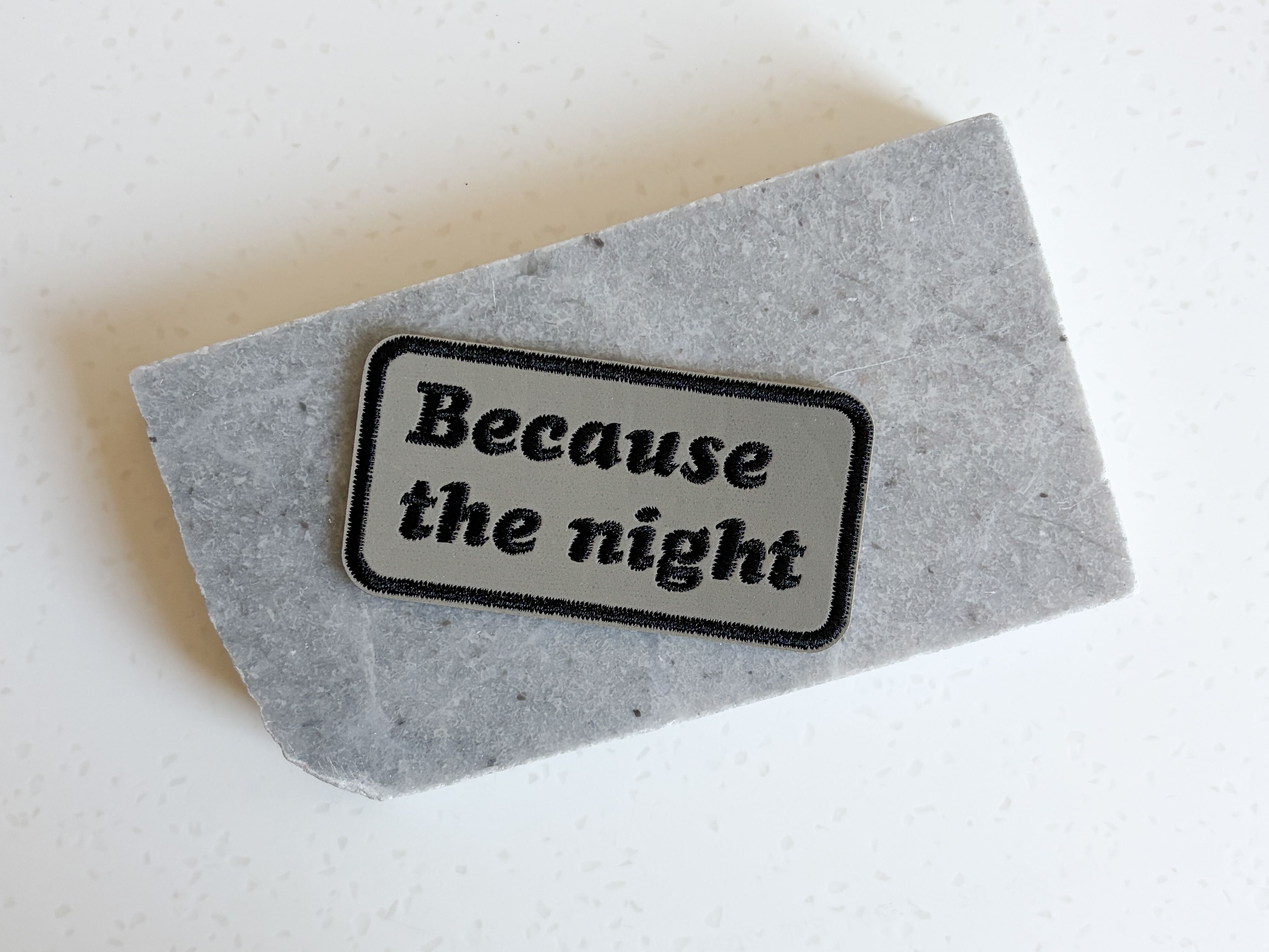 A patch that reads "because the night"