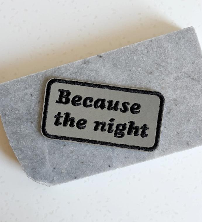 A patch that reads "because the night"